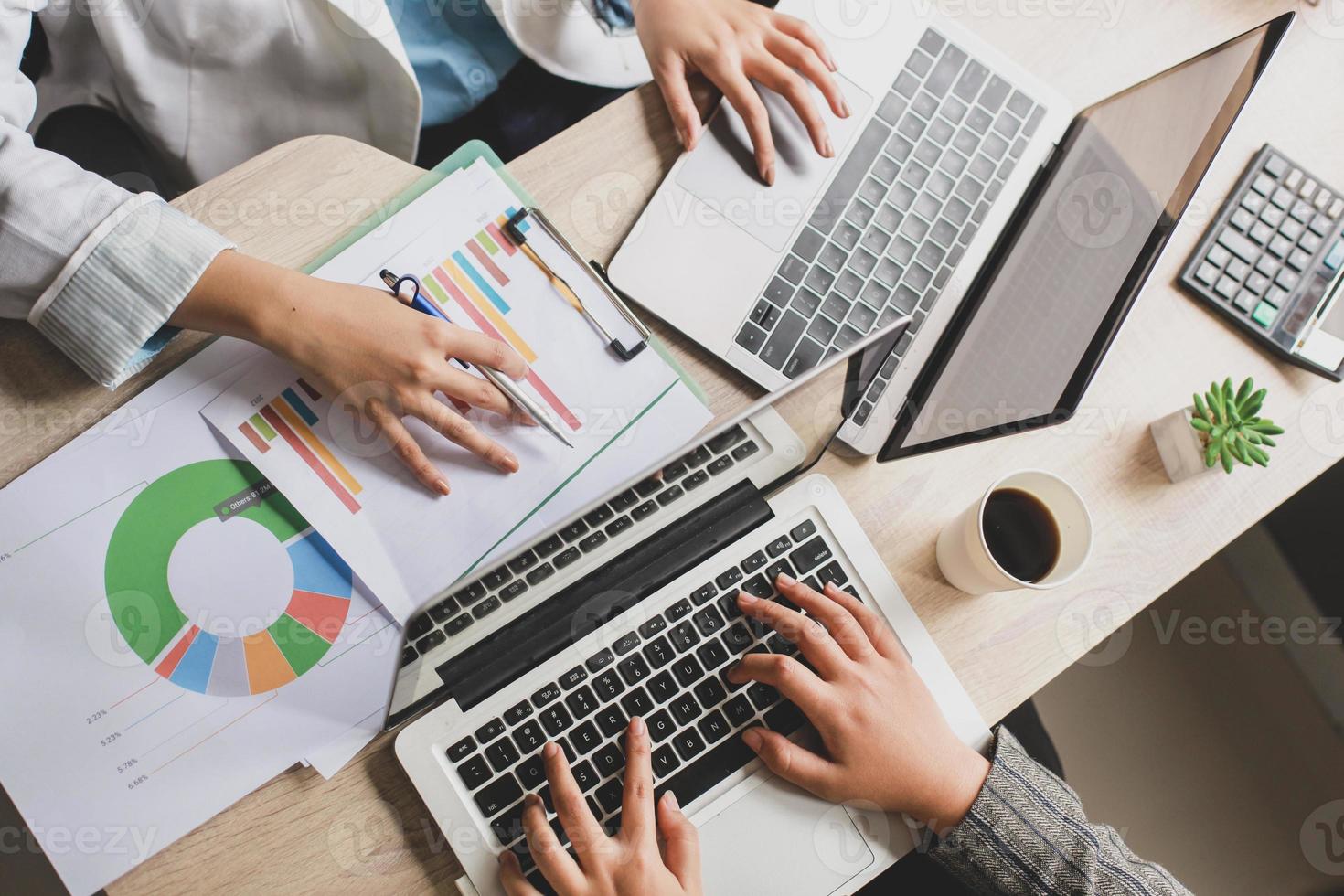 vista superior das atividades duas trabalhadoras na mesa de escritório, duas mulheres de negócios trabalhando no laptop e digitando no teclado na mesa do escritório. foto