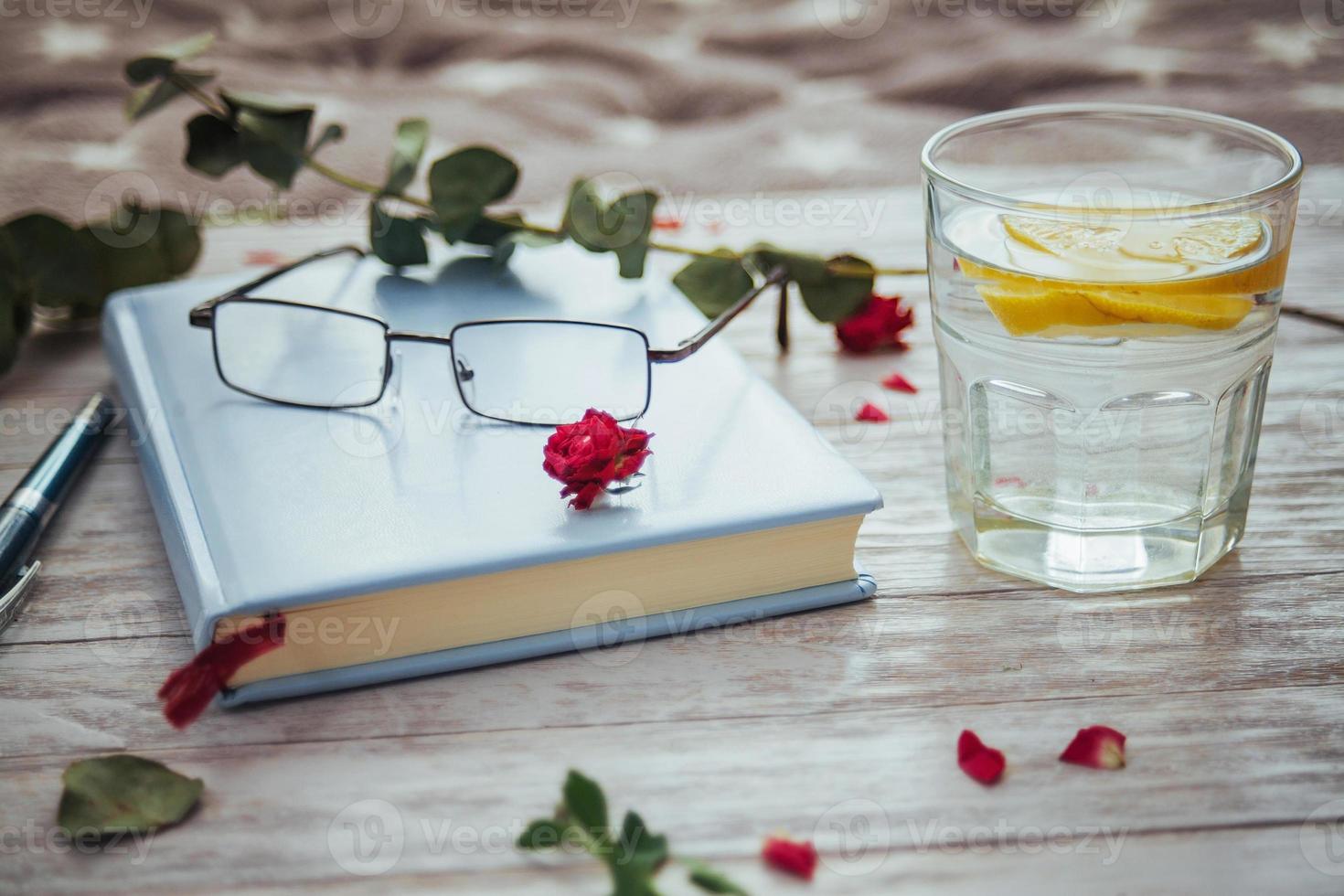 óculos de livro e pétalas de flores foto