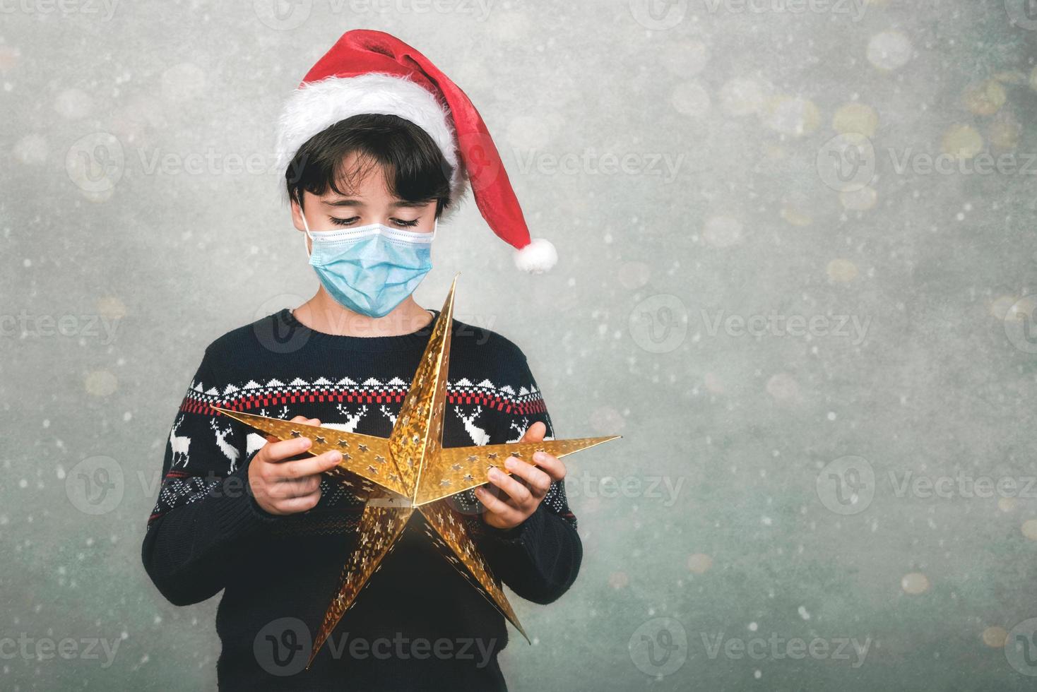 feliz natal, criança com máscara médica e estrela de natal foto