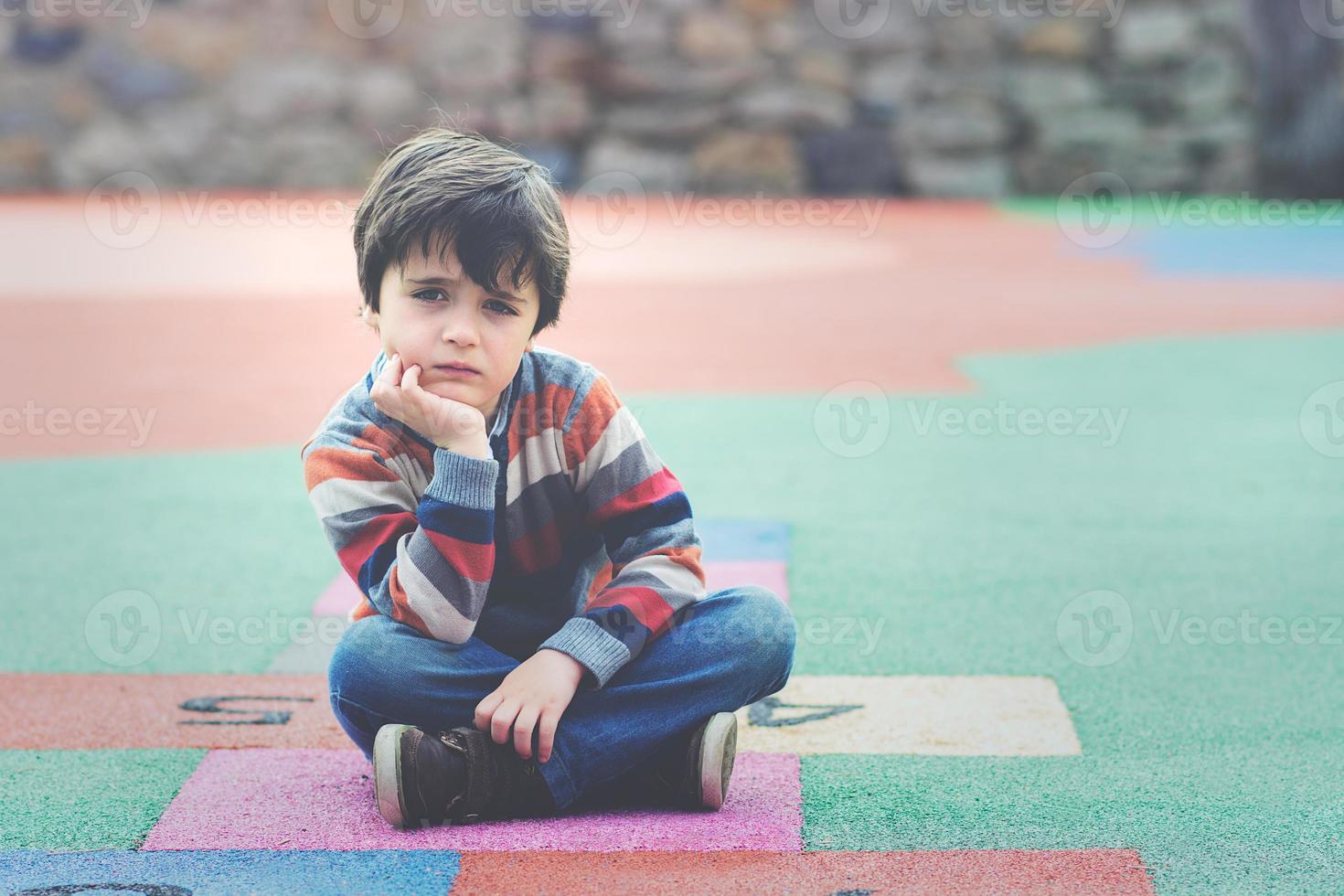 menino triste sentado no chão foto