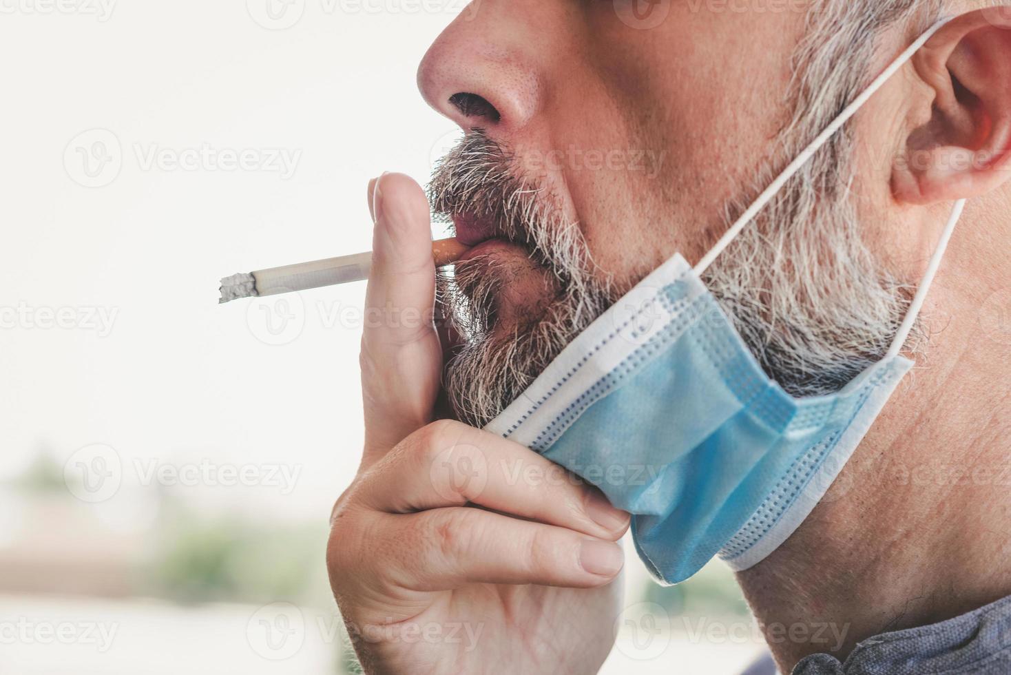 covid-19, homem com máscara médica fumando um cigarro no fundo da rua blur foto