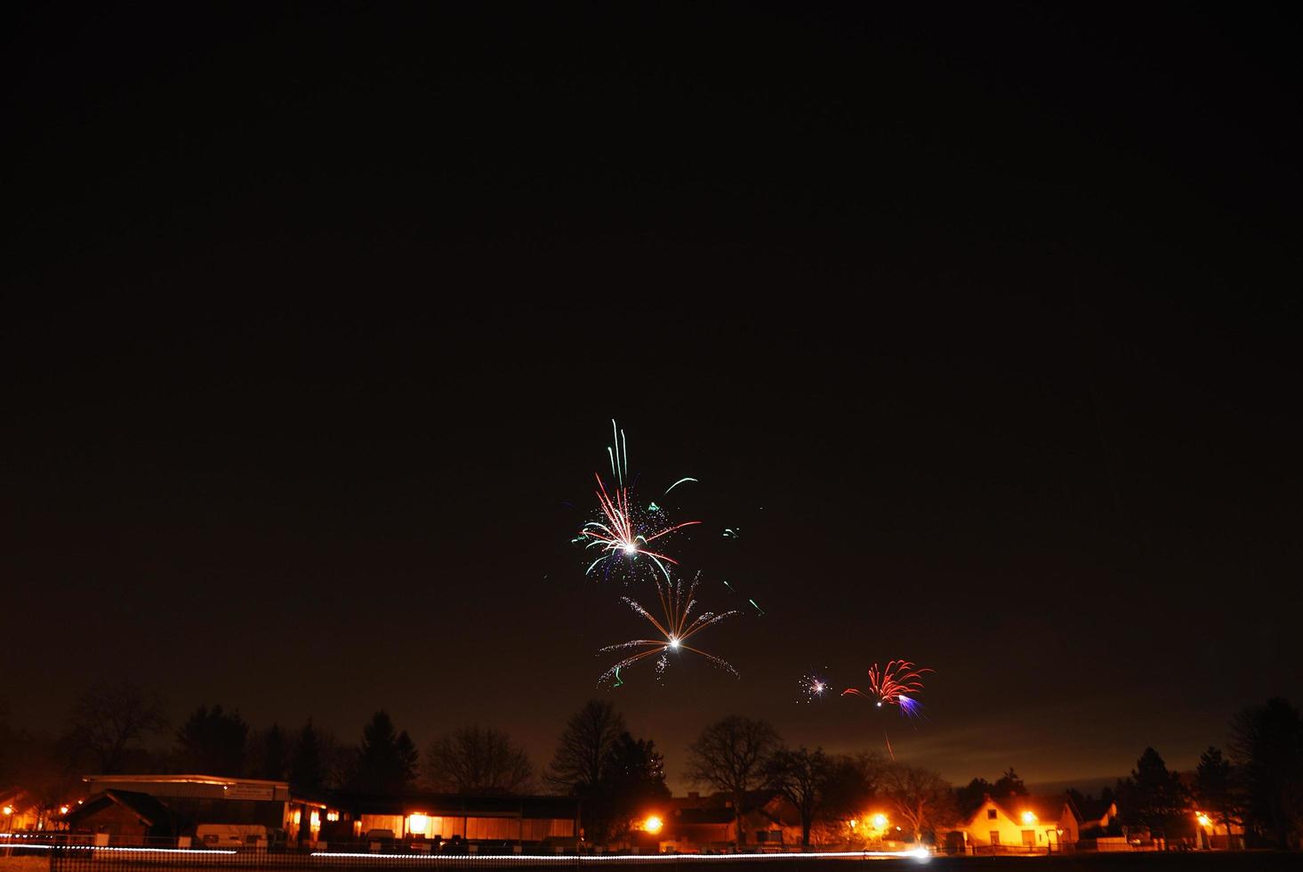 celebração de véspera de ano novo na vila com fogos de artifício coloridos foto