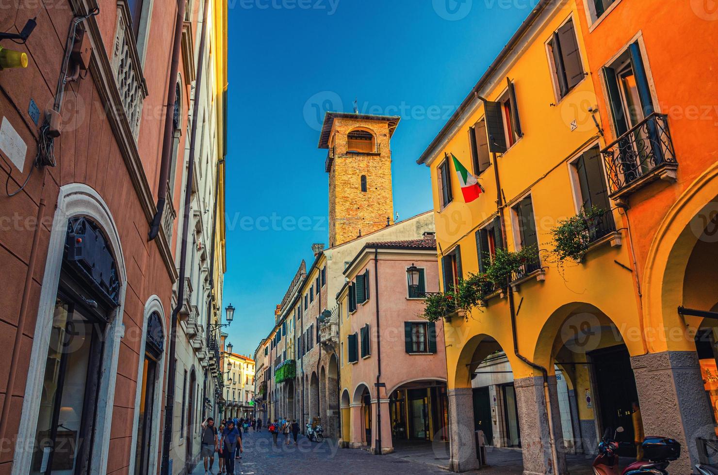 rua com antigos edifícios coloridos com bandeira italiana na parede e torre no centro histórico medieval da cidade de pádua foto