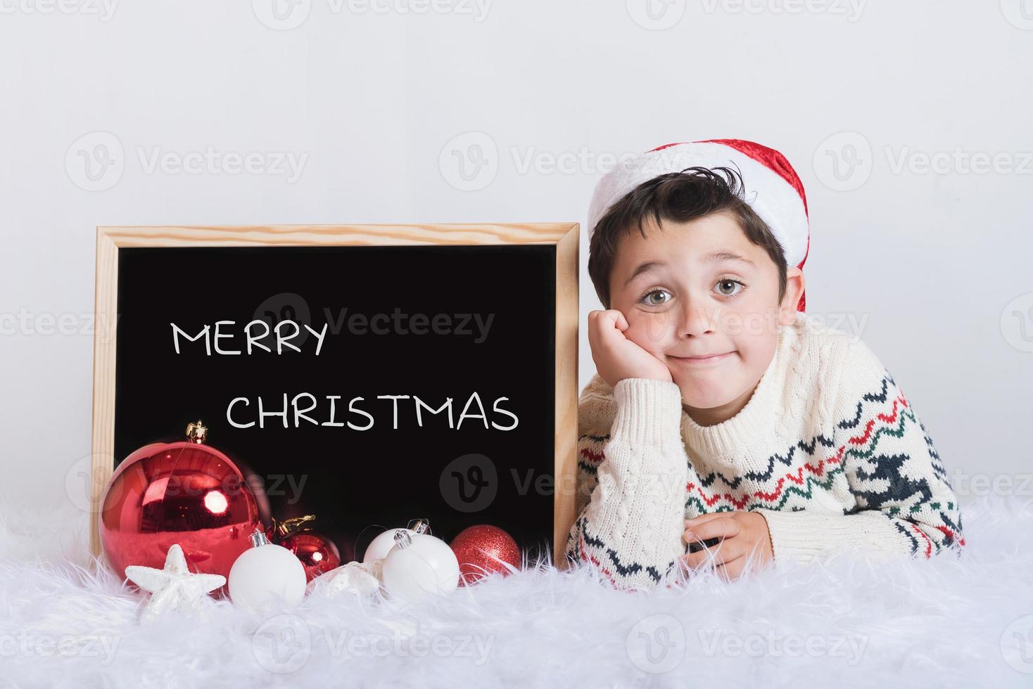 menino sorridente com um quadro-negro no natal foto