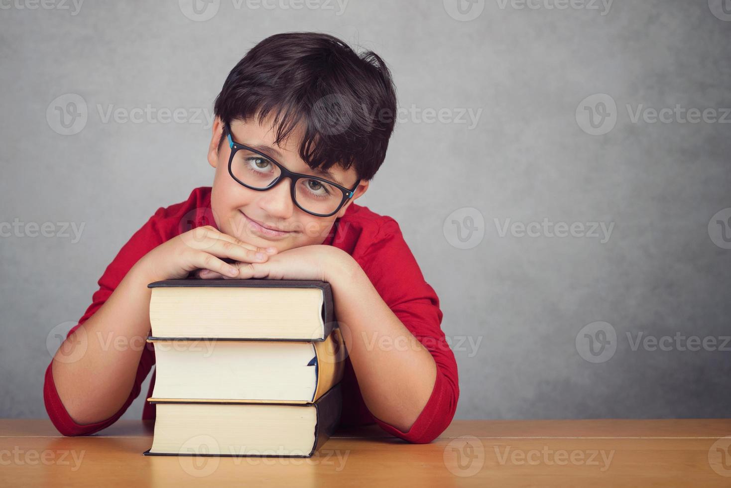 menino sorridente, apoiando-se em livros foto