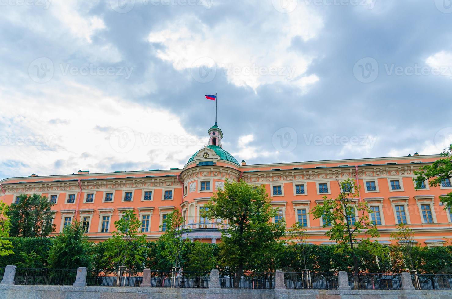 castelo mikhailovsky com bandeira russa no fundo do céu dramático azul, são petersburgo foto