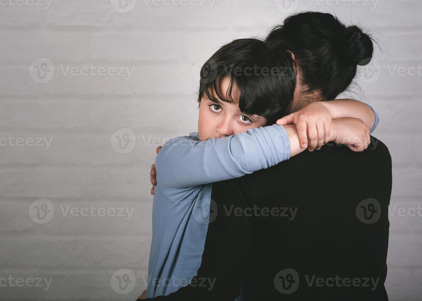 criança triste abraçando sua mãe foto