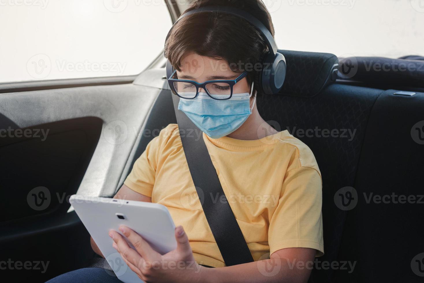 garoto com máscara médica andando de carro foto