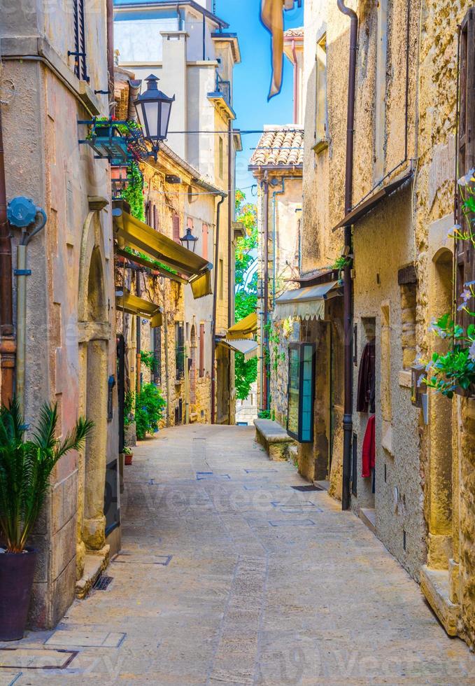 rua de paralelepípedos italiana típica com edifícios tradicionais e casas com plantas verdes foto