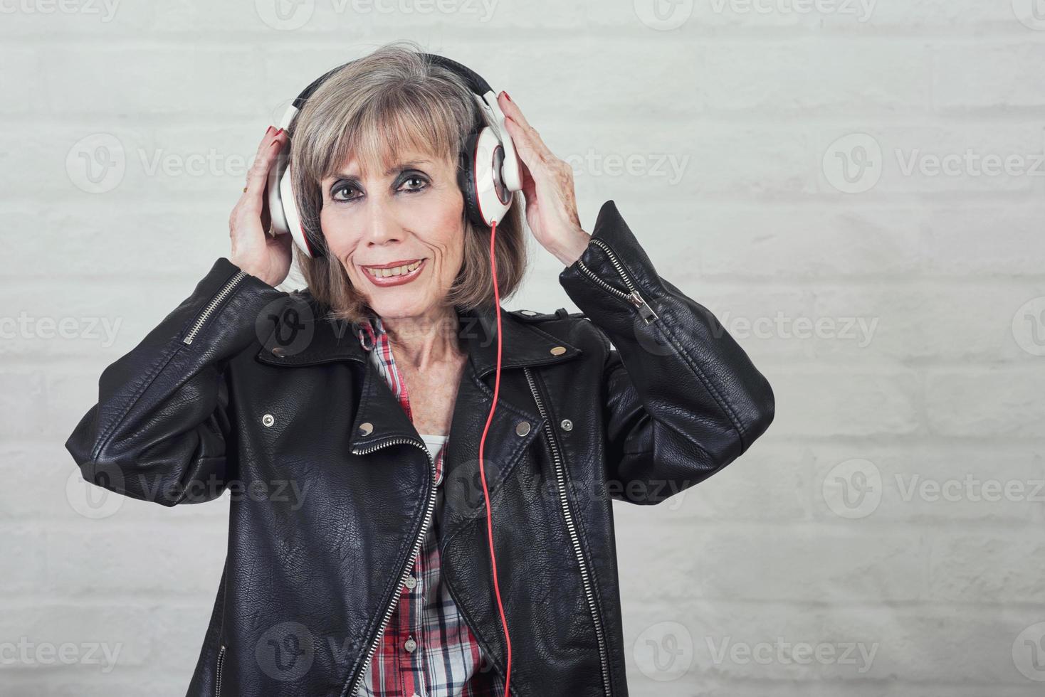 mulher sênior sorridente com fones de ouvido ouvindo música foto