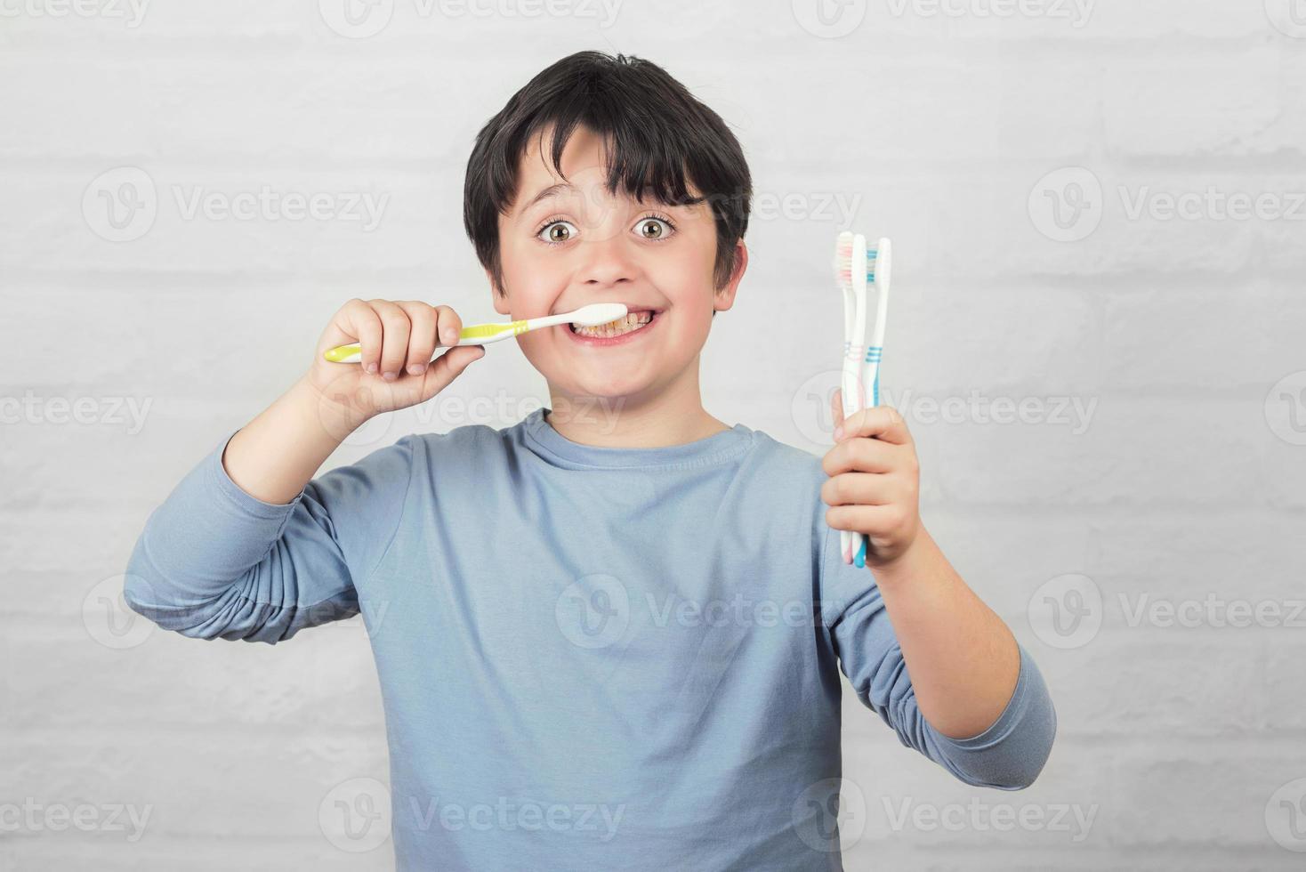 criança feliz, limpando os dentes pela escova de dentes foto