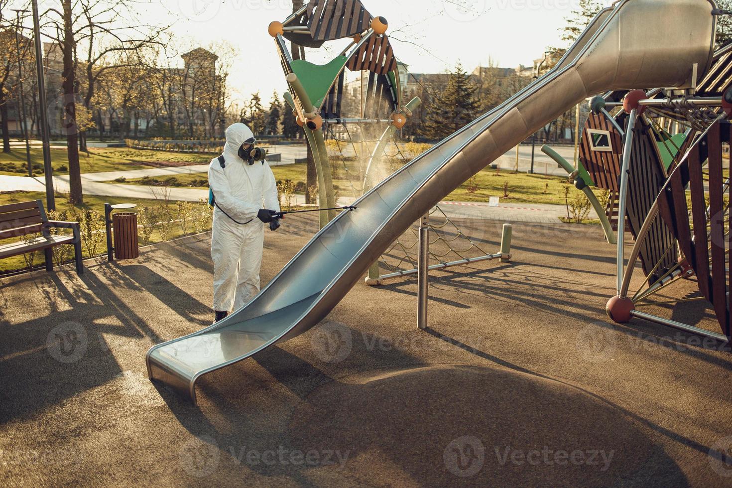 limpeza e desinfecção no playground no complexo da cidade em meio às equipes de epidemia de coronavírus para esforços de desinfecção prevenção de infecções e controle de traje de proteção e máscara epidêmica foto