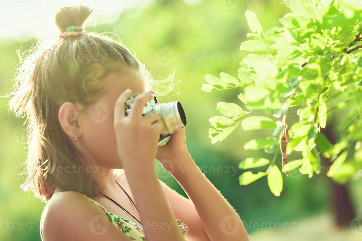 fotógrafo iniciante. uma garotinha tira fotos de uma árvore em sua câmera fotográfica de filme