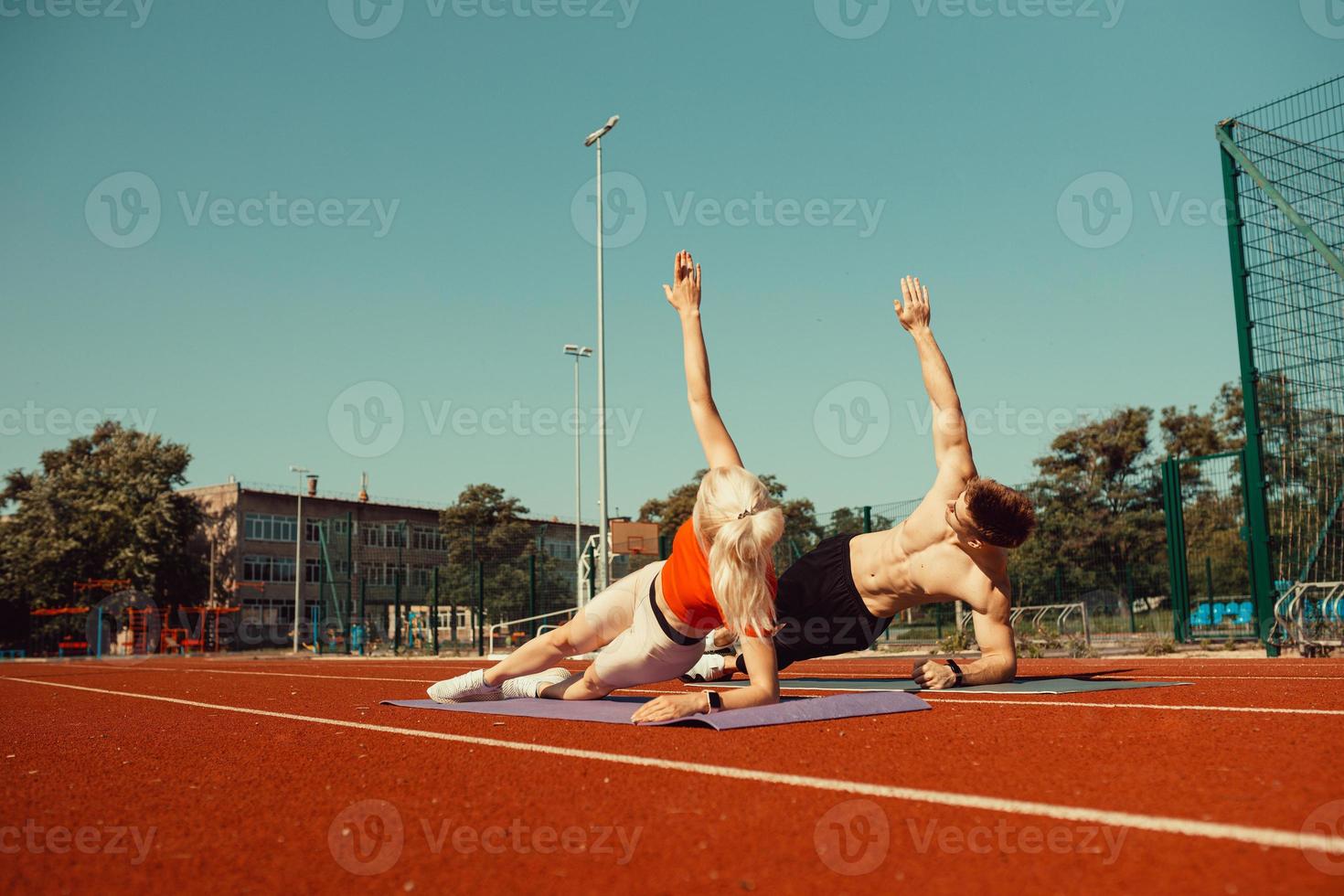 jovem casal praticando esportes no estádio deitado em tapetes de ioga foto