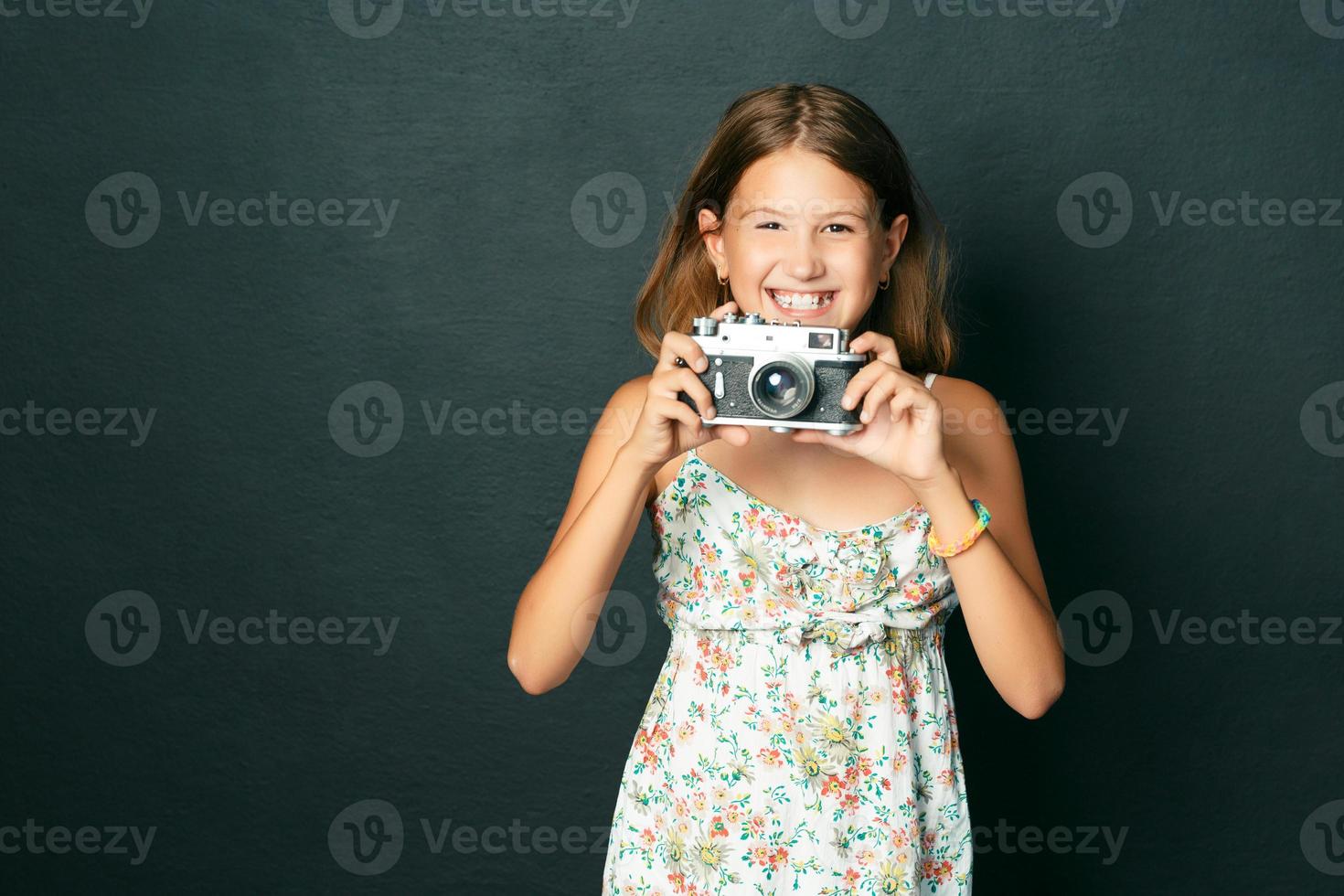 linda garota sorridente com dentes brancos, segurando uma câmera instantânea foto