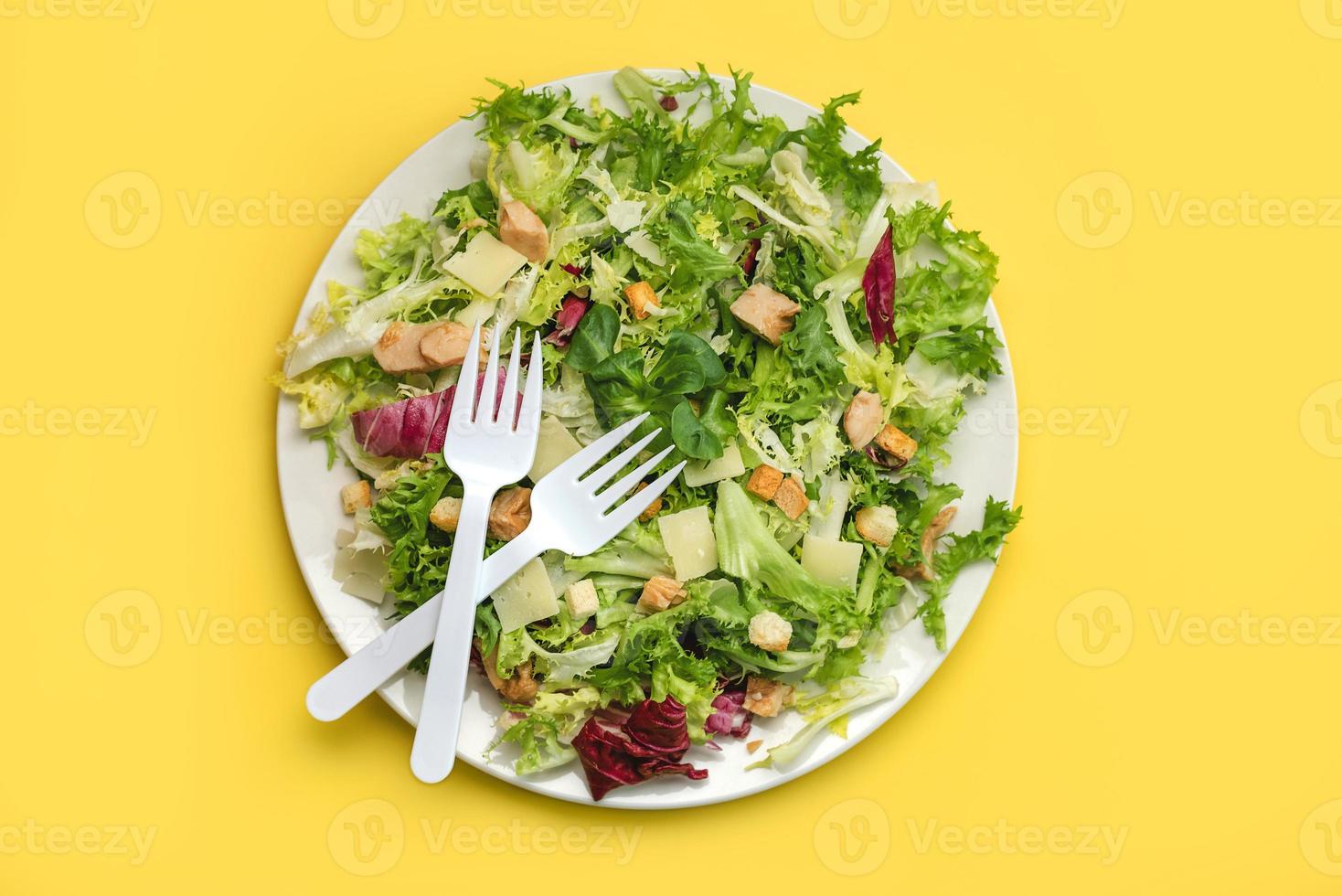 garfos brancos em uma salada de alface, escarola, rúcula com queijo, frango e croutons.conceito de comida saudável foto