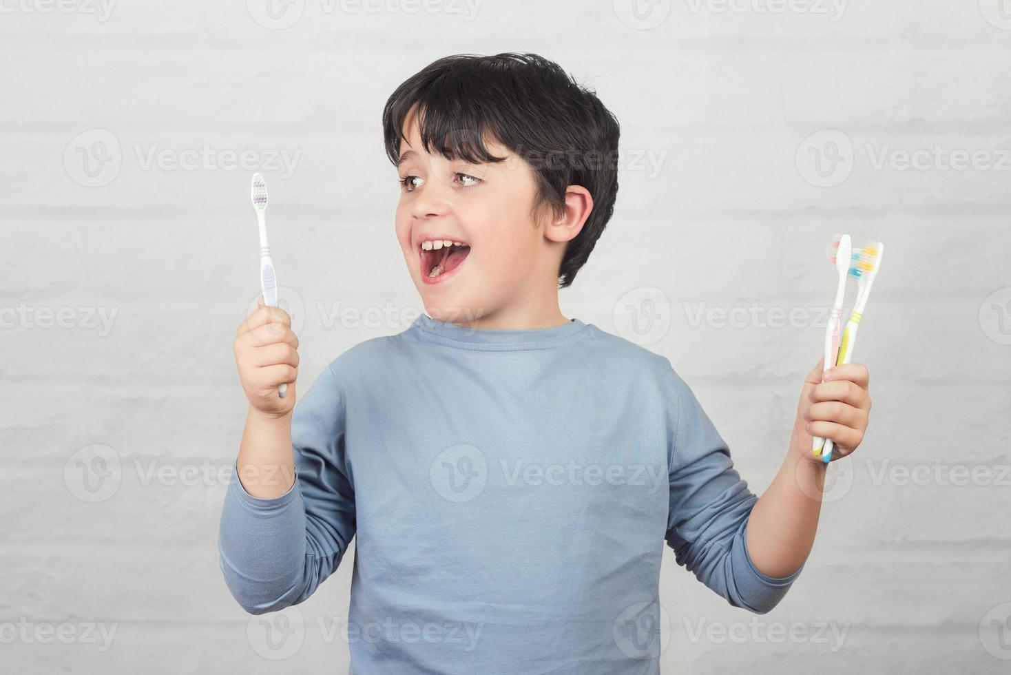 criança feliz, limpando os dentes pela escova de dentes foto