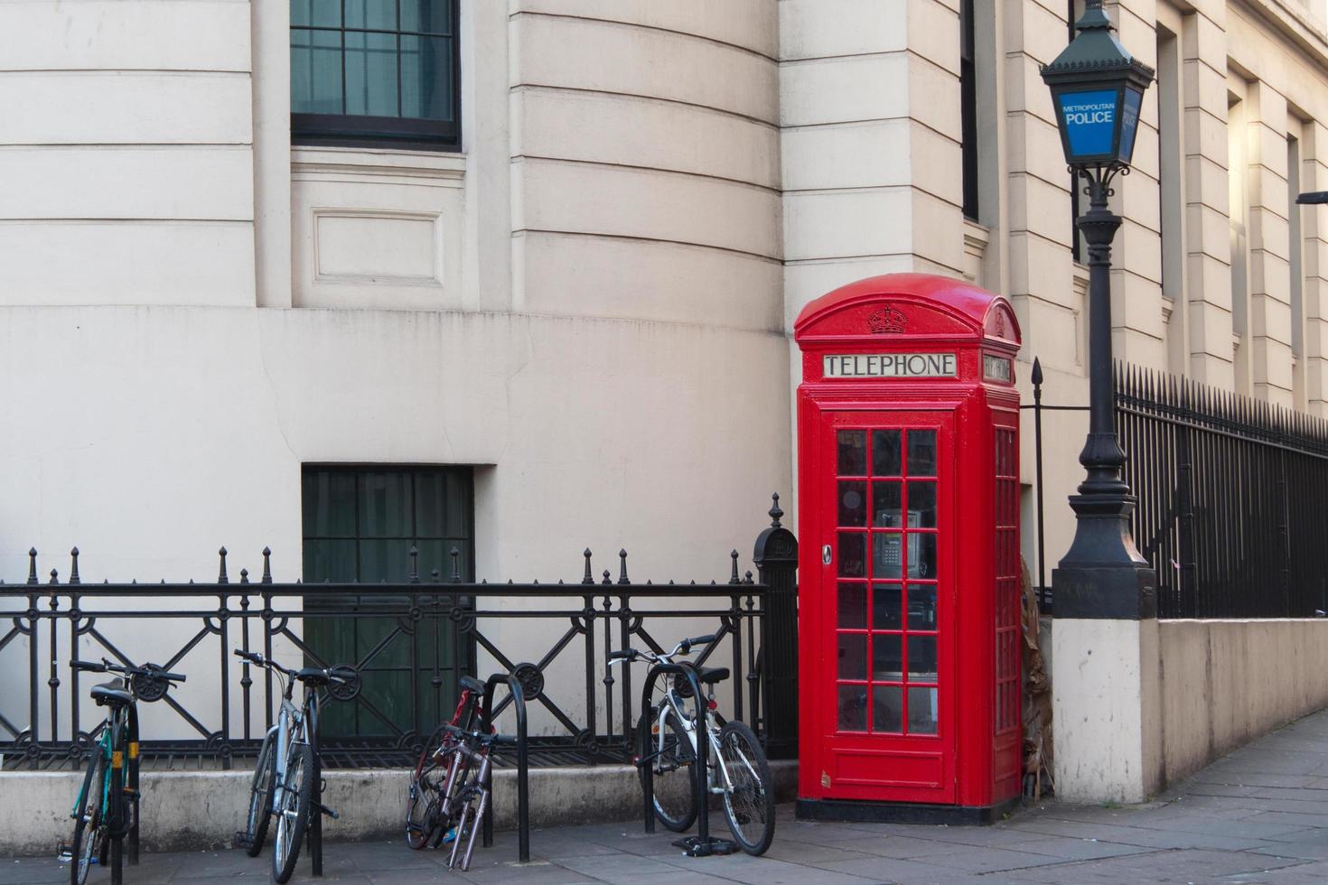 cabine telefônica britânica vermelha e algumas bicicletas. rua de londres, sem pessoas foto