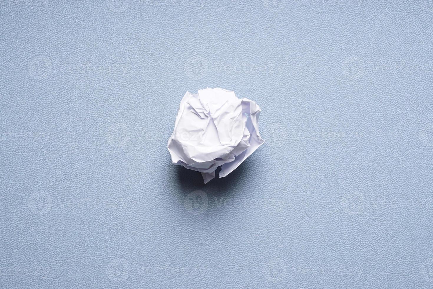 bola de papel amassada em fundo azul foto