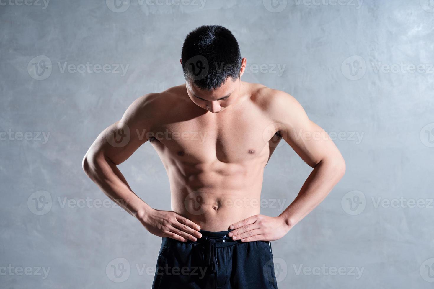 homem asiático musculoso posando em fundo cinza foto