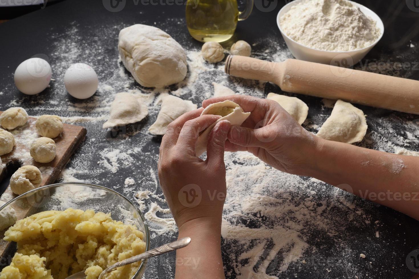 mulher esculpe bolinhos com batatas artesanais em um fundo preto. tiro do ângulo superior. cozinha popular ucraniana. foto