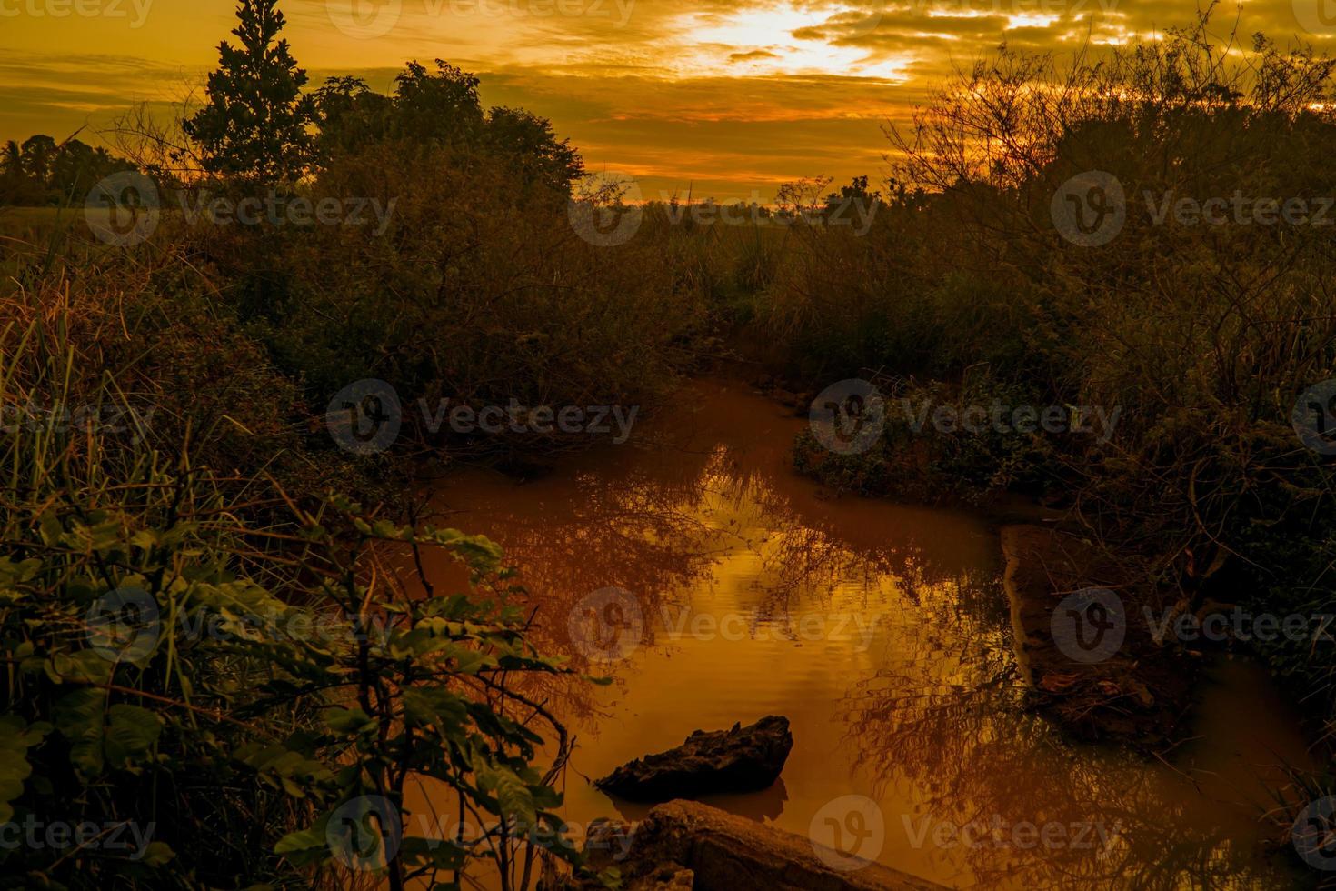 rio ao pôr do sol calmo. o sol está coberto por nuvens foto