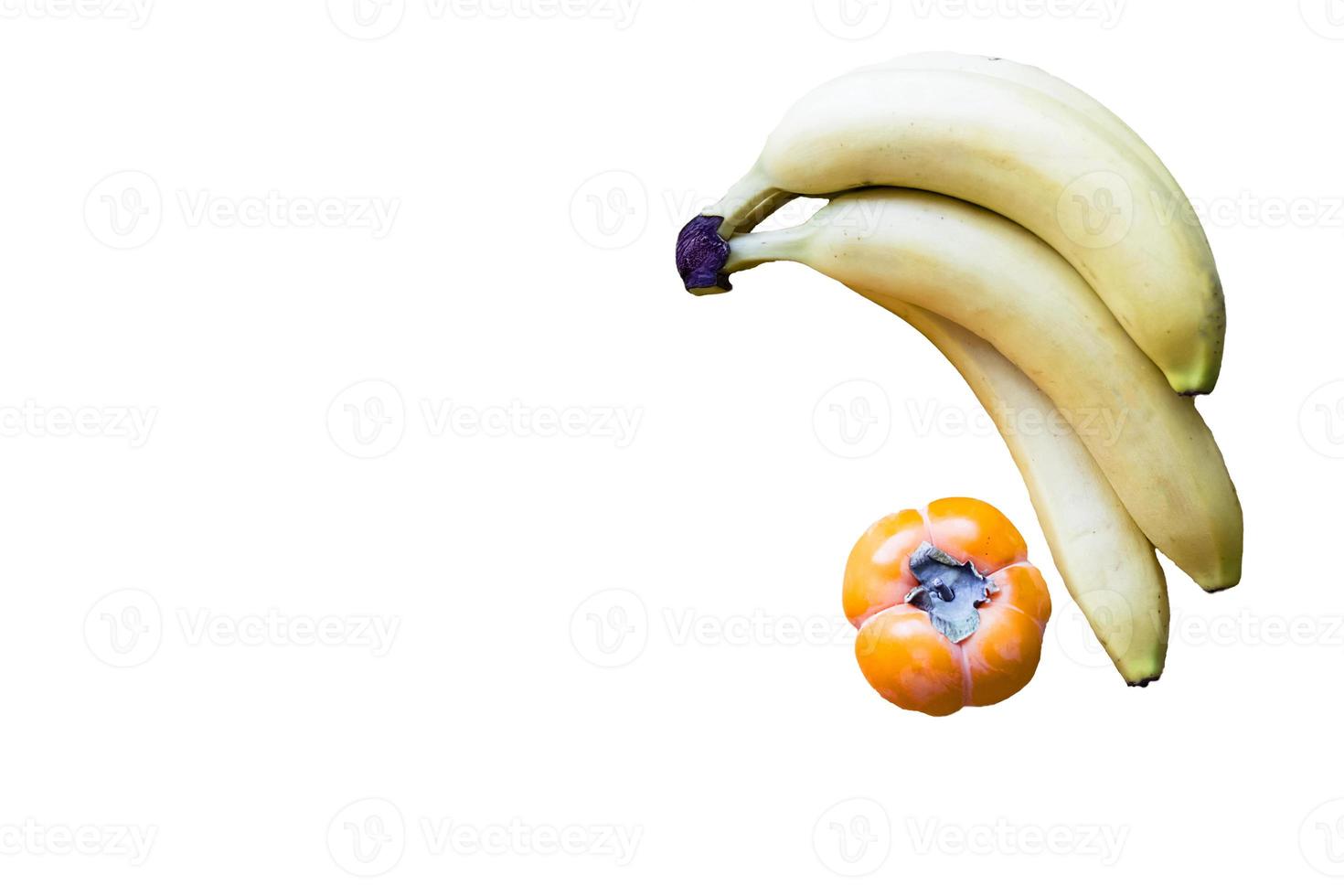 banana fresca e caqui em fundo branco e mesa de madeira, foto