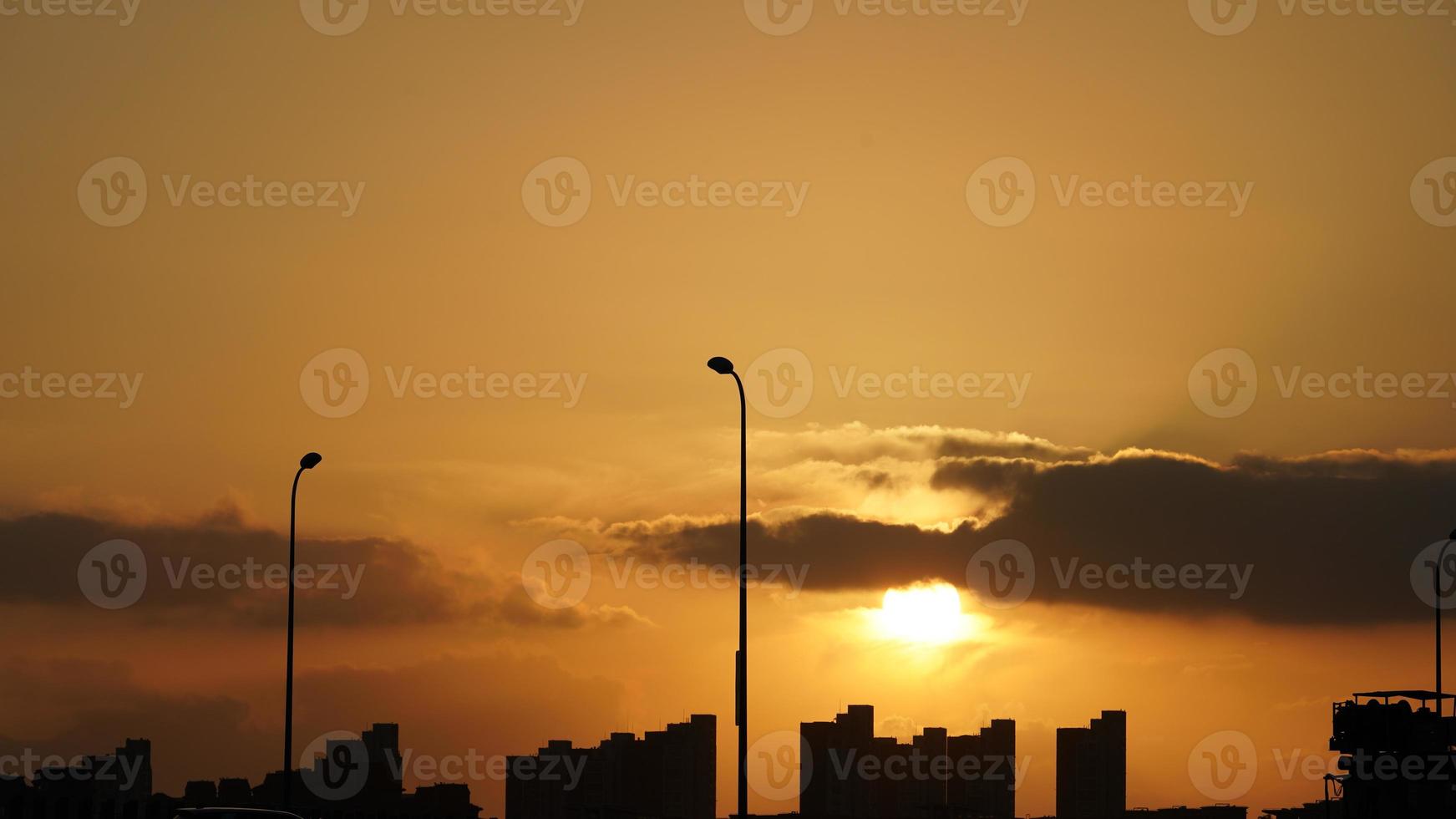 a bela vista do pôr do sol com a silhueta e o céu de nuvens coloridas na cidade foto