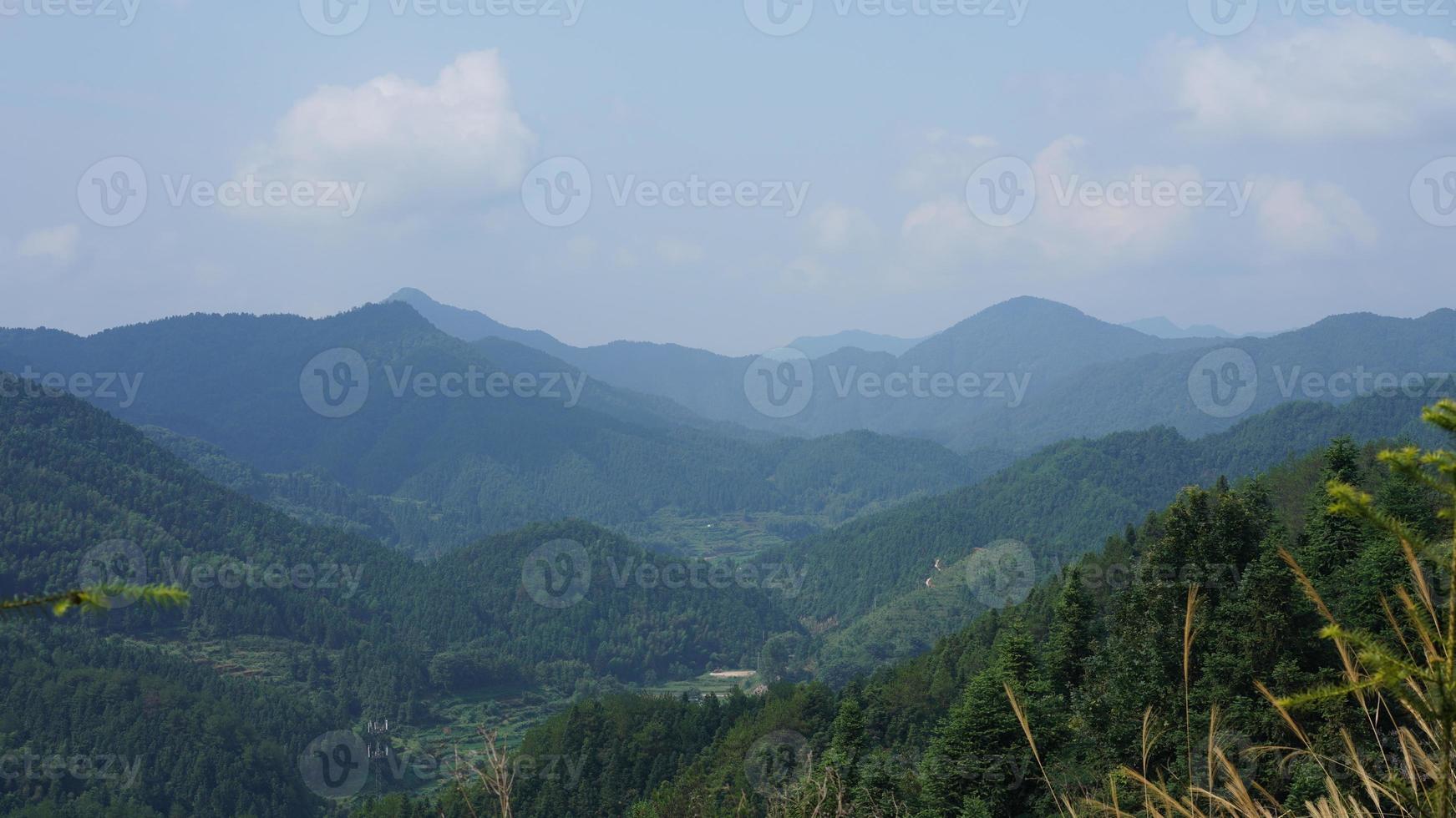 as belas paisagens de montanhas com a floresta verde e a pequena vila como pano de fundo no interior da China foto