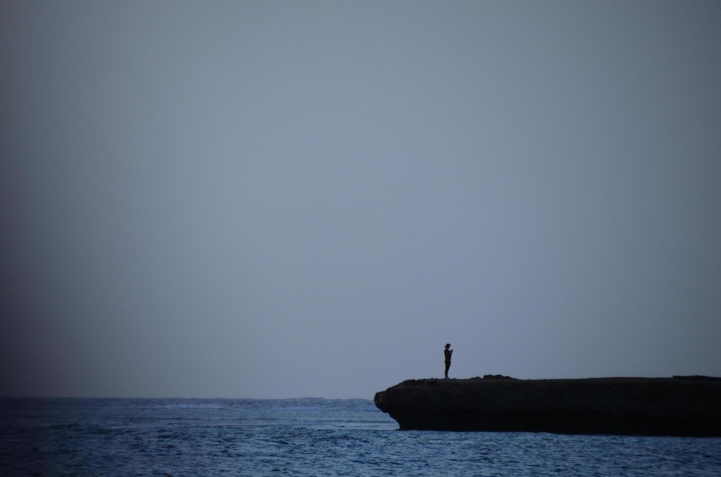 mulher em uma pedra no mar foto