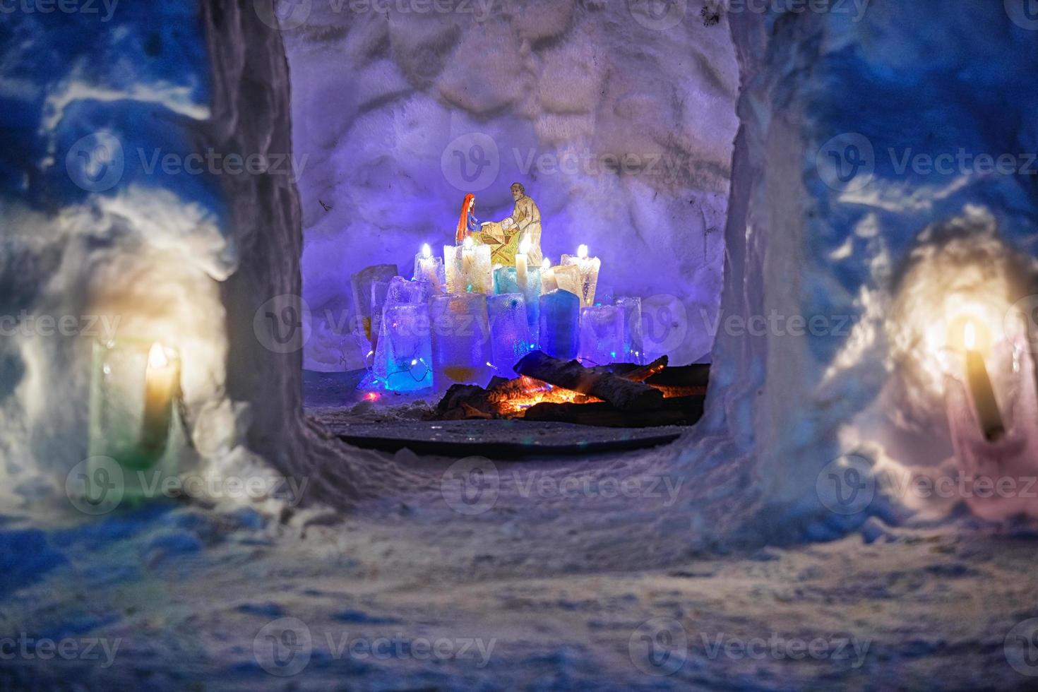 instalação sobre o tema de natal dentro da casa de neve com plafonds gelados coloridos e velas acesas neles na noite fria de inverno. vista pela porta. foto