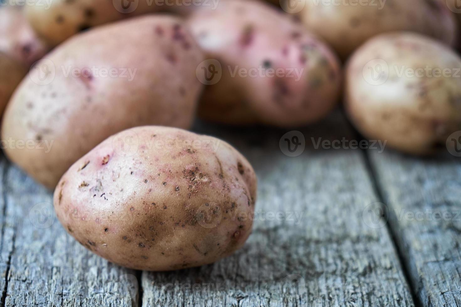 tubérculos de batata crua com casca, deitado sobre as tábuas de madeira áspera foto