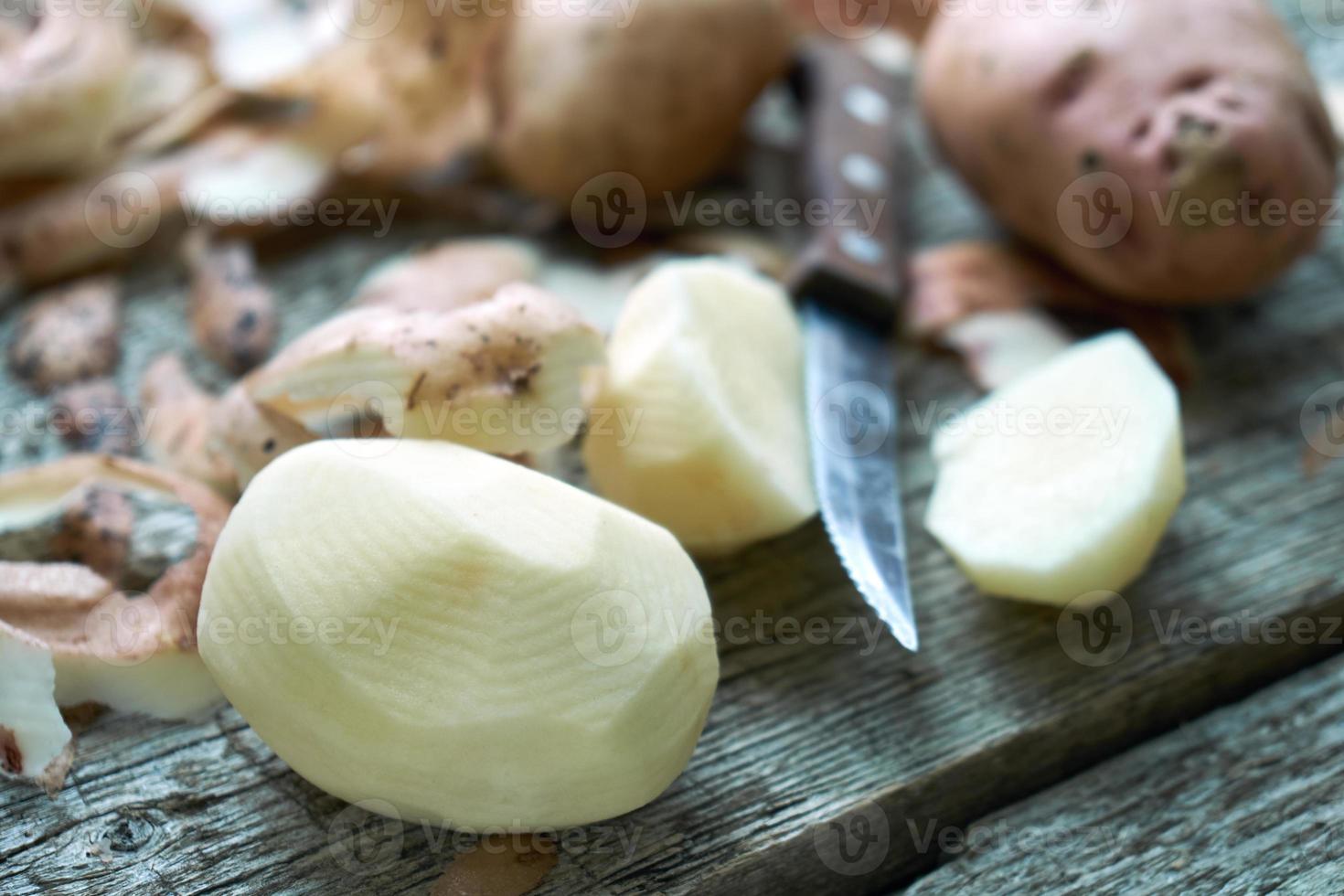 batata descascando nas tábuas de madeira áspera de uma mesa de campo foto