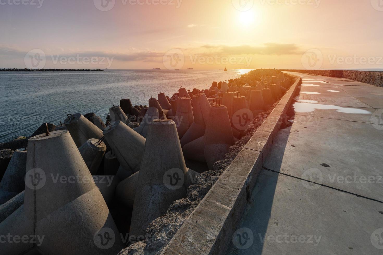 cais norte com quebra-mares, paisagem do sol, farol moderno à luz do sol, tetrápodes ao longo das bordas do cais, bela paisagem à noite. foto