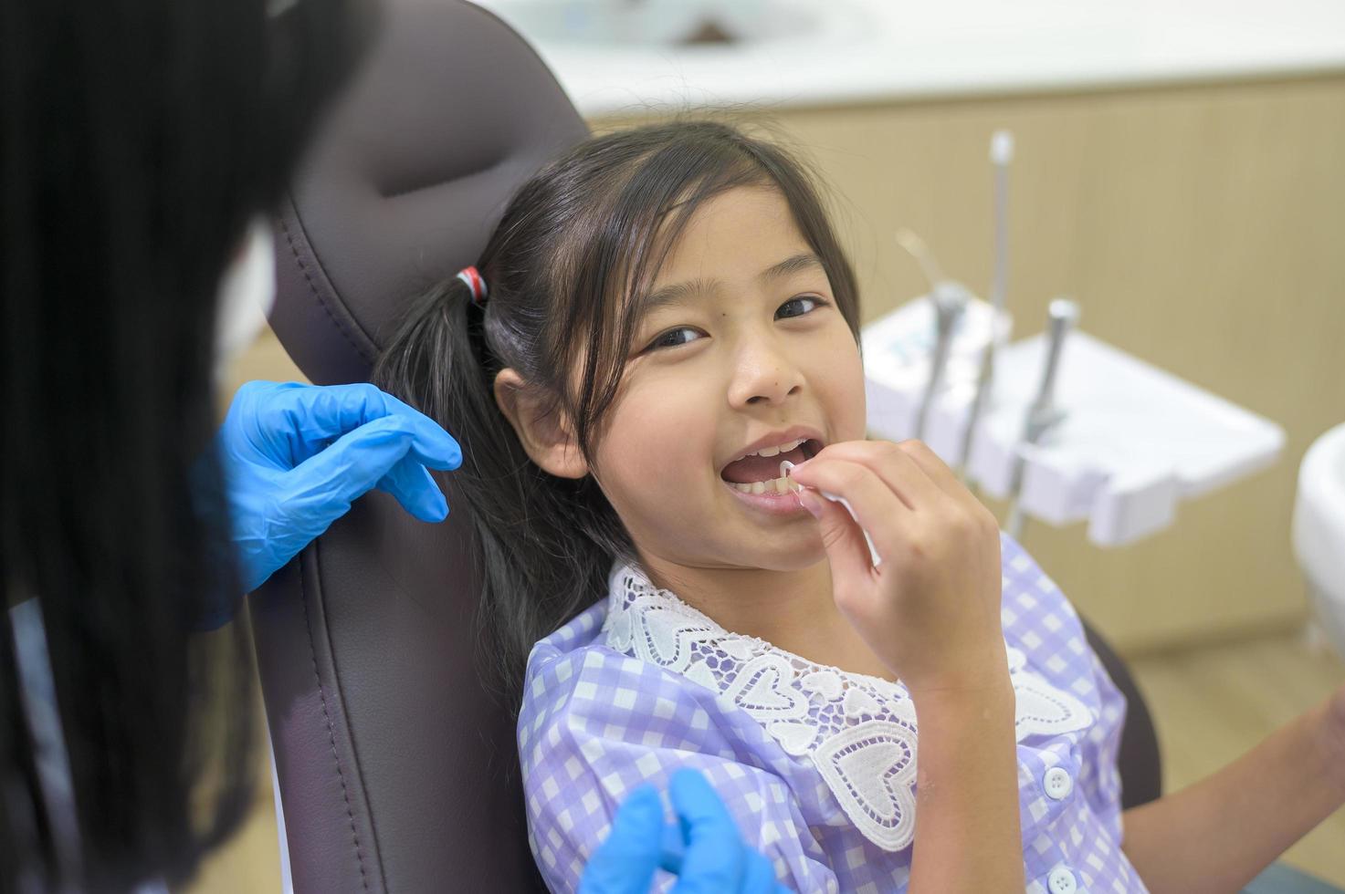 uma menina bonita tendo os dentes examinados pelo dentista na clínica odontológica, check-up de dentes e conceito de dentes saudáveis foto