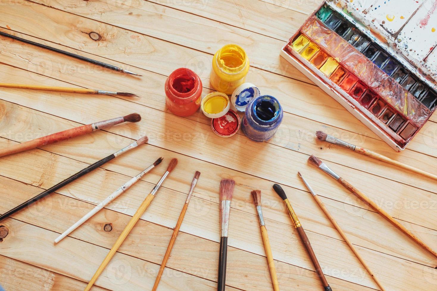 pincel de arte e tintas coloridas em latas em um fundo escuro. foto