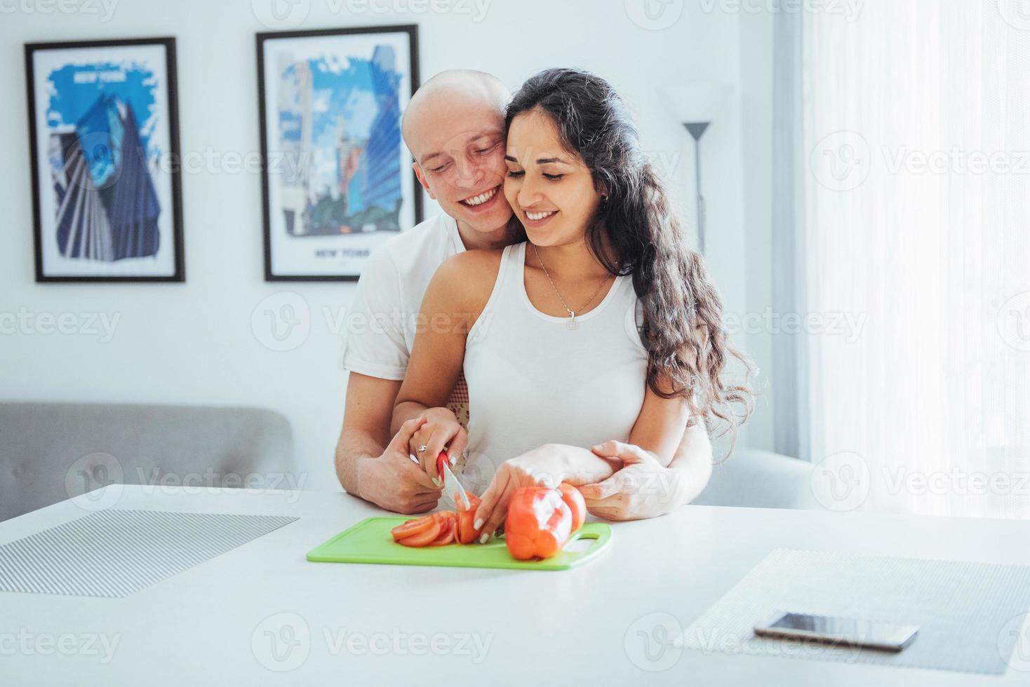 lindo casal jovem mói legumes juntos na cozinha. foto