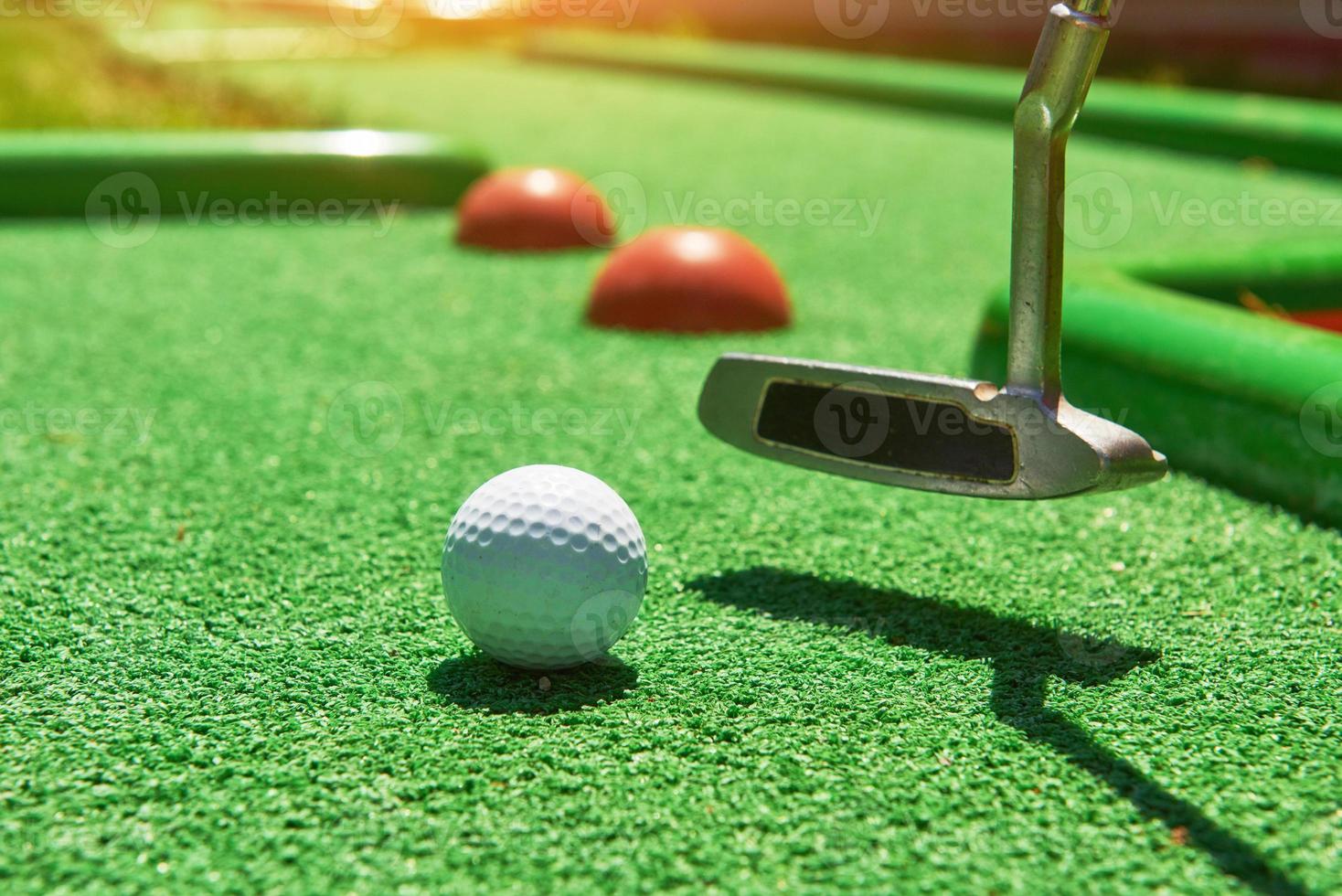 bola de golfe e taco de golfe na grama artificial foto