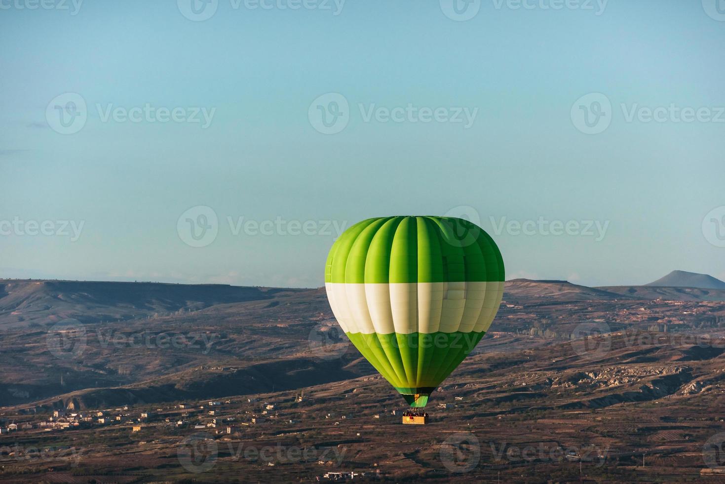balão de ar quente voando sobre a paisagem rochosa na capadócia, turquia. vale, ravina, colinas, localizada entre as montanhas vulcânicas foto