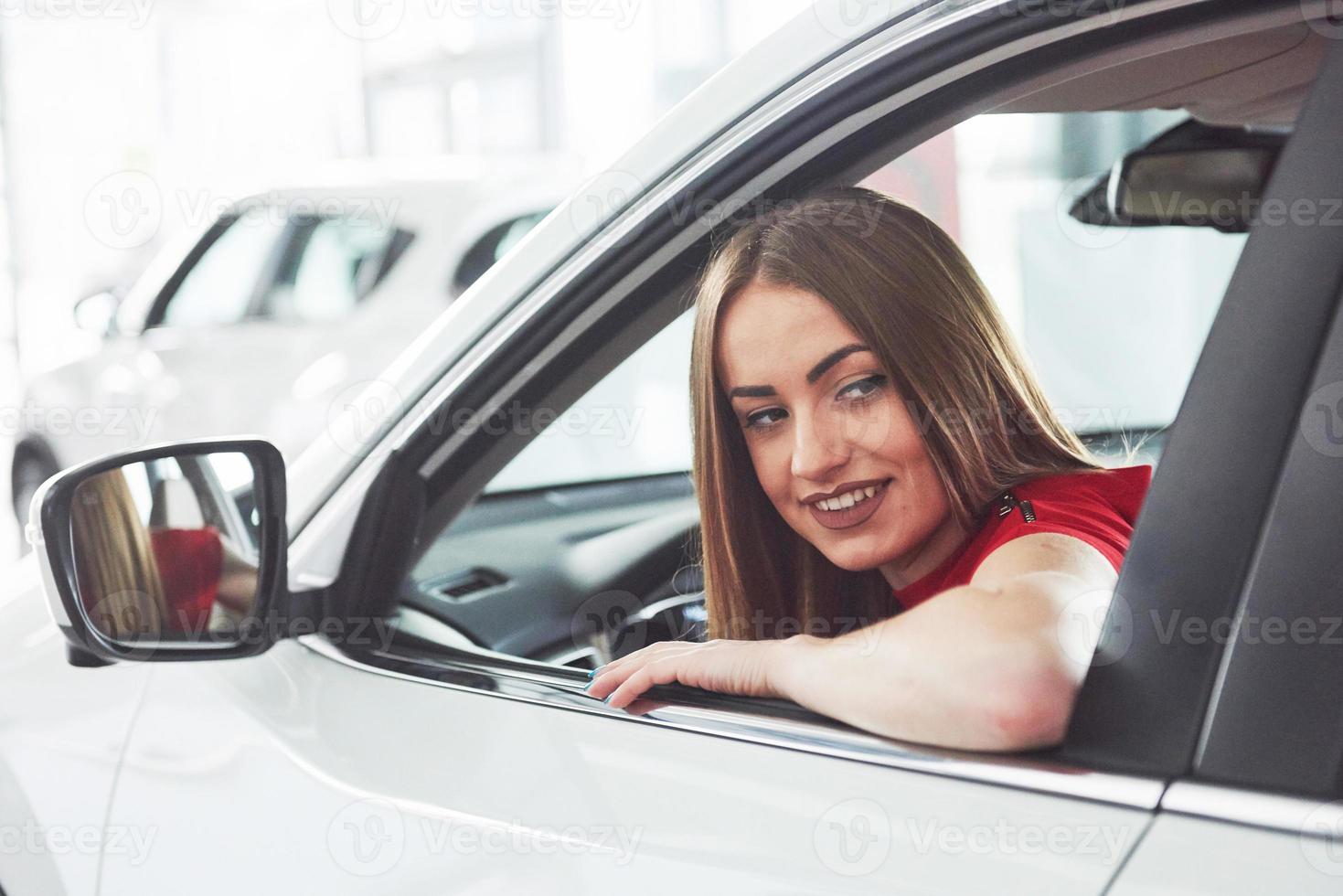 mulher no carro interno mantém a roda girando sorrindo olhando para os passageiros no banco de trás idéia motorista de táxi contra raios do sol luz brilho céu conceito de veículo de exame - segunda casa a garota foto