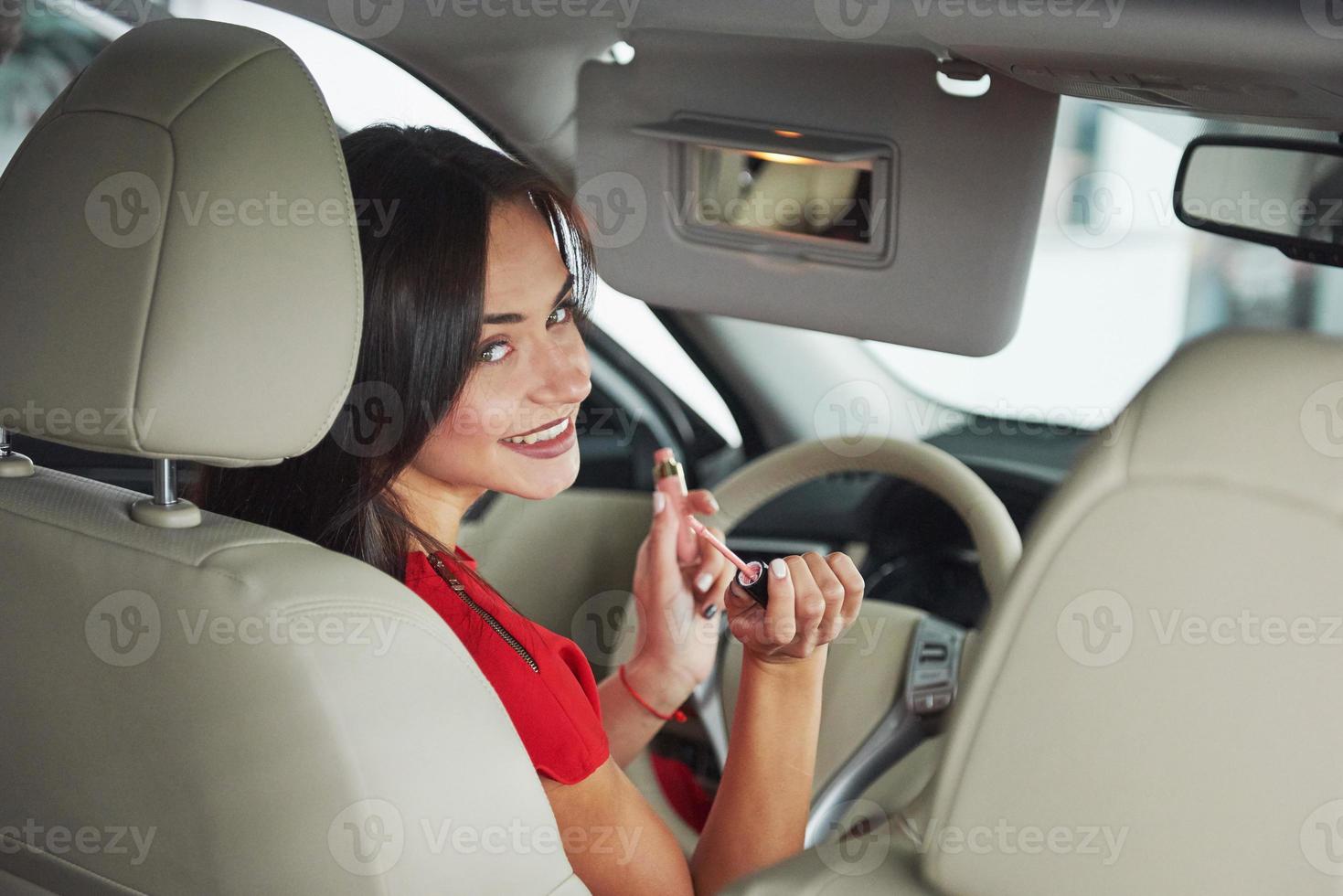 mulher no carro interno mantém a roda girando sorrindo olhando para os passageiros no banco de trás idéia motorista de táxi contra raios do sol luz brilho céu conceito de veículo de exame - segunda casa a garota foto