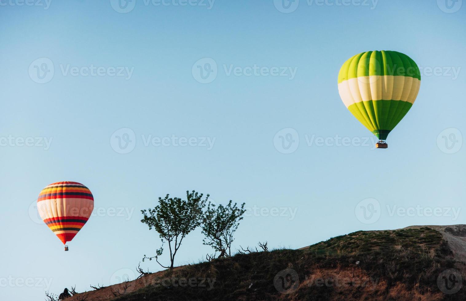 balão de ar quente voando sobre a paisagem rochosa na capadócia, turquia. vale, ravina, colinas, localizada entre as montanhas vulcânicas foto