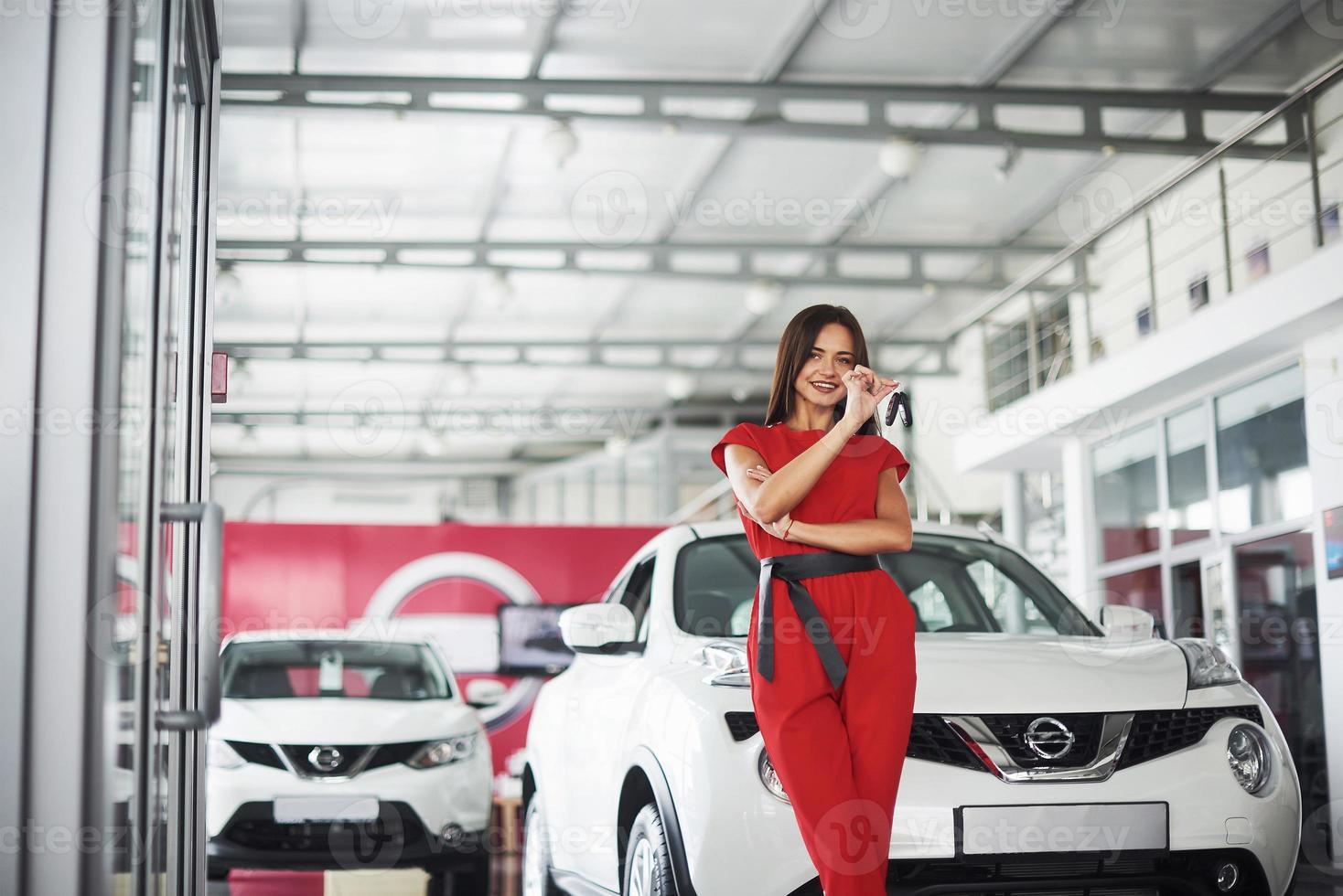 vendedor de carros sorridente entregando suas novas chaves de carro, concessionária e conceito de vendas. menina feliz o comprador foto