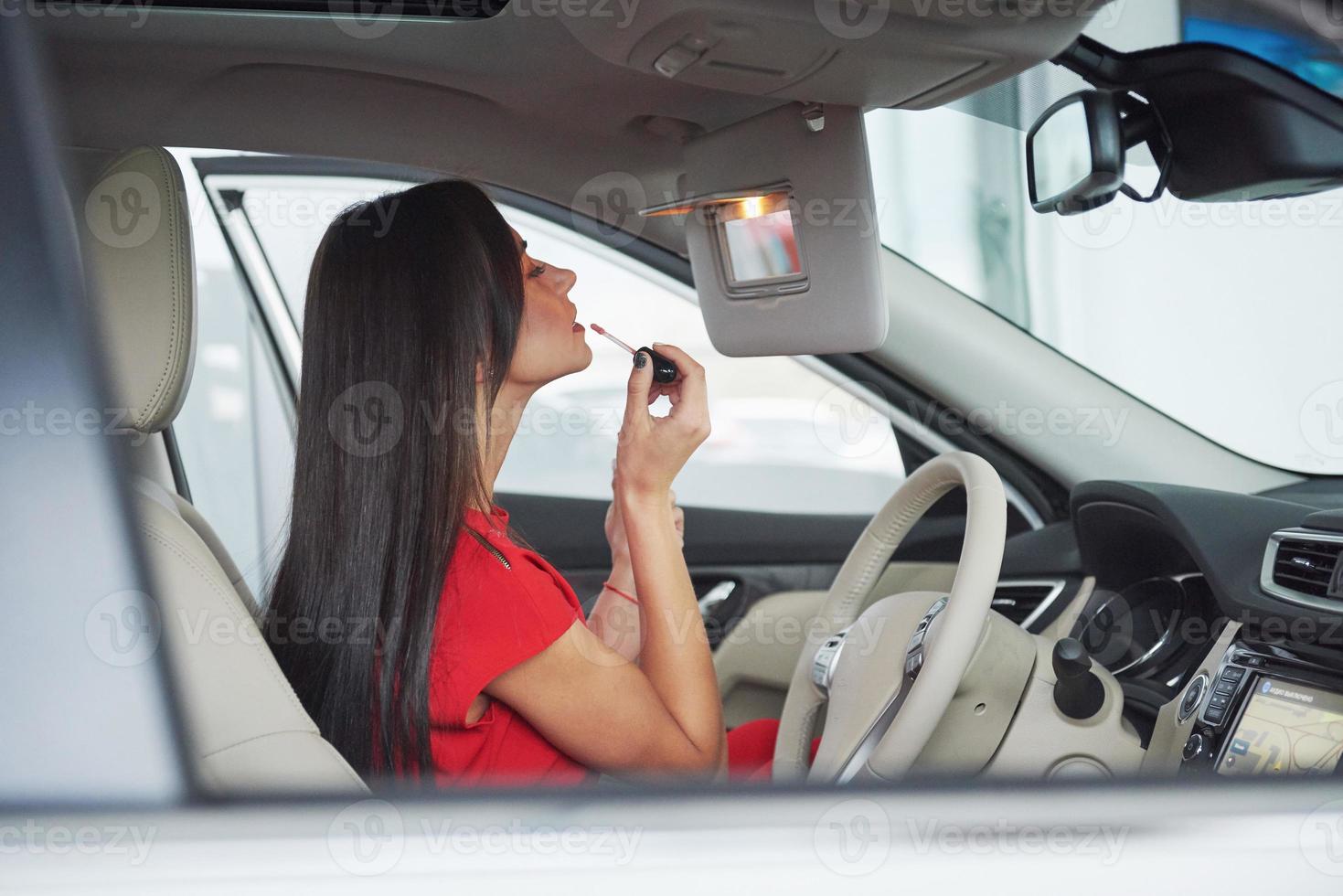 mulher no carro interno mantém a roda girando sorrindo olhando para os passageiros no banco de trás idéia motorista de táxi contra raios do sol luz brilho céu conceito de veículo de exame - segunda casa a garota foto