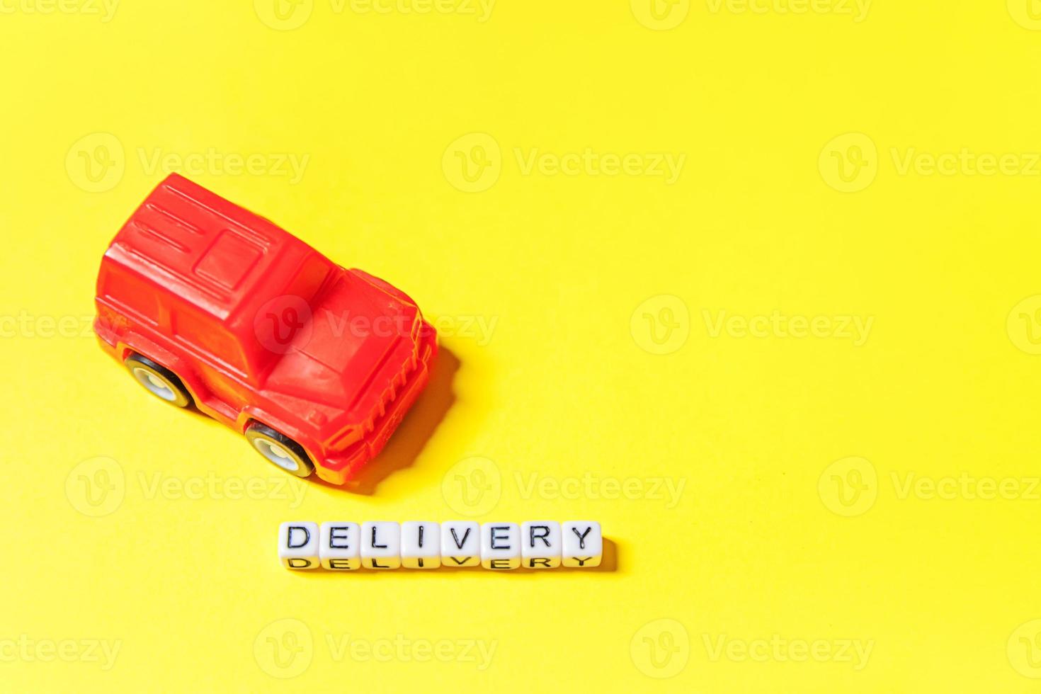 simplesmente projete o carro de brinquedo vermelho e a palavra de entrega de inscrição isolada em fundo colorido amarelo. compras na internet compra on-line pacotes de comércio eletrônico conceito de serviço de entrega espaço de cópia foto