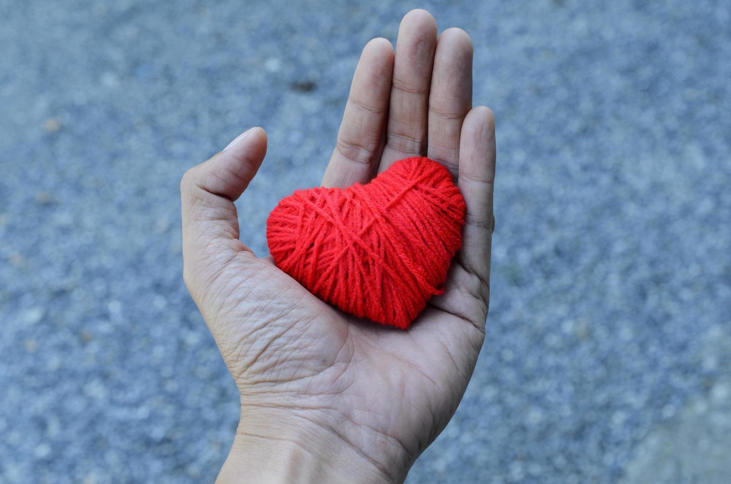 forma de coração vermelho feito de fio de linha na mão para o amor dia dos namorados foto
