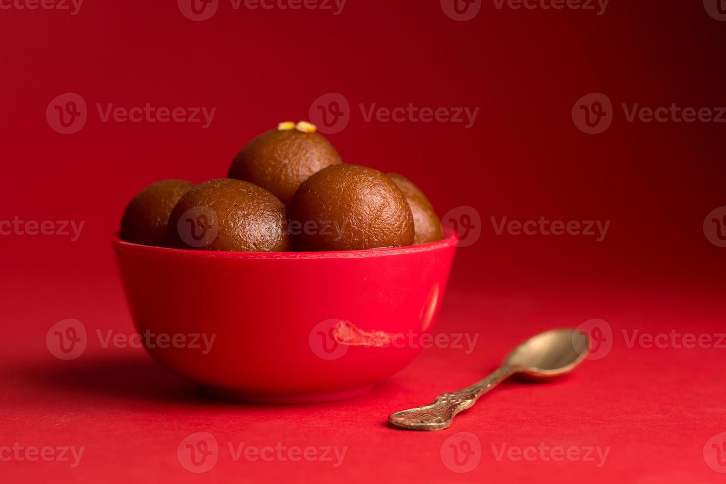 gulab jamun em tigela vermelha sobre fundo vermelho. sobremesa indiana ou prato doce. foto