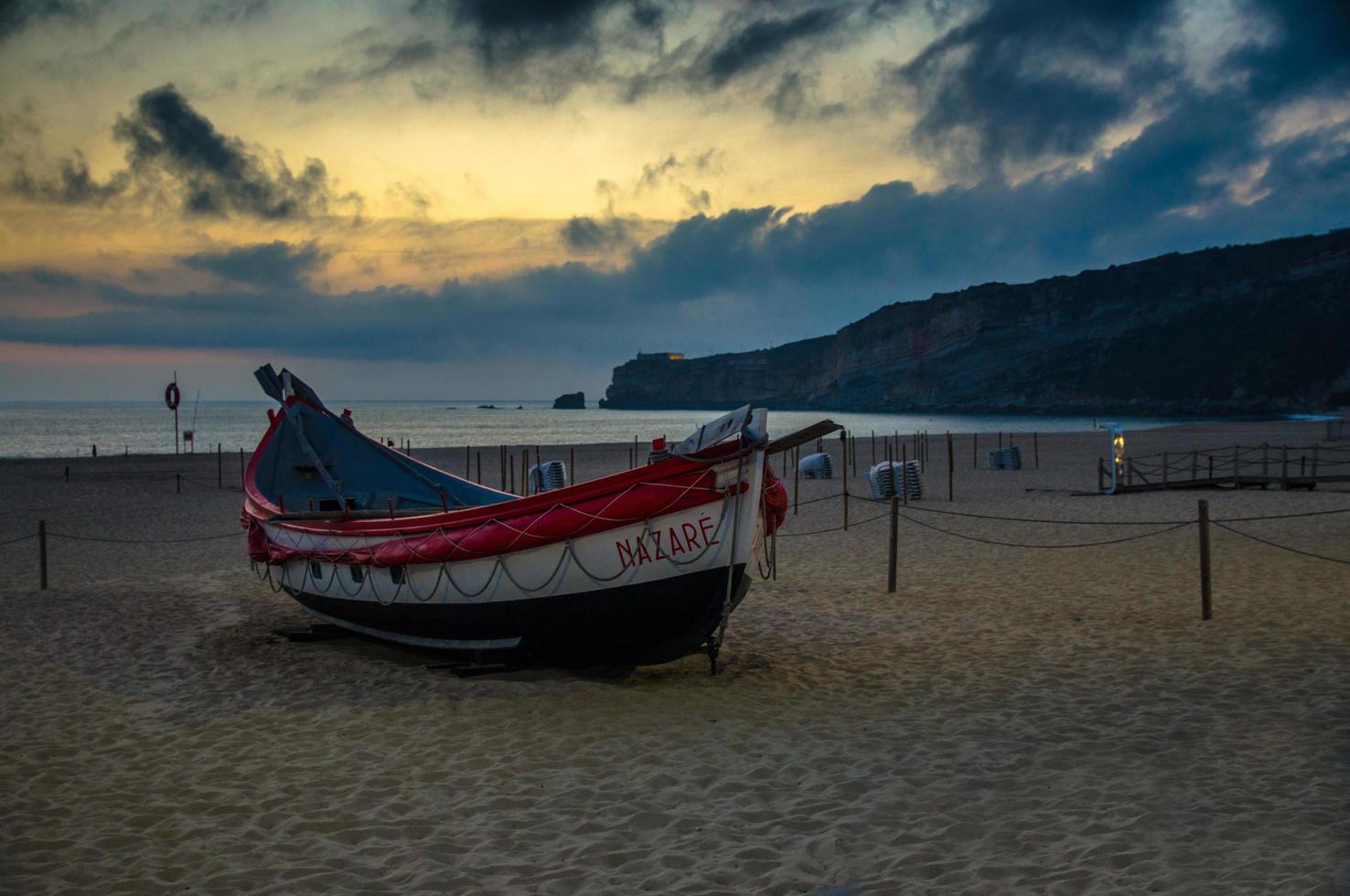 nazaré, portugal - 21 de junho de 2017 barcos de pesca tradicionais na praia de nazaré ao pôr do sol crepúsculo crepúsculo, portugal, oceano atlântico foto