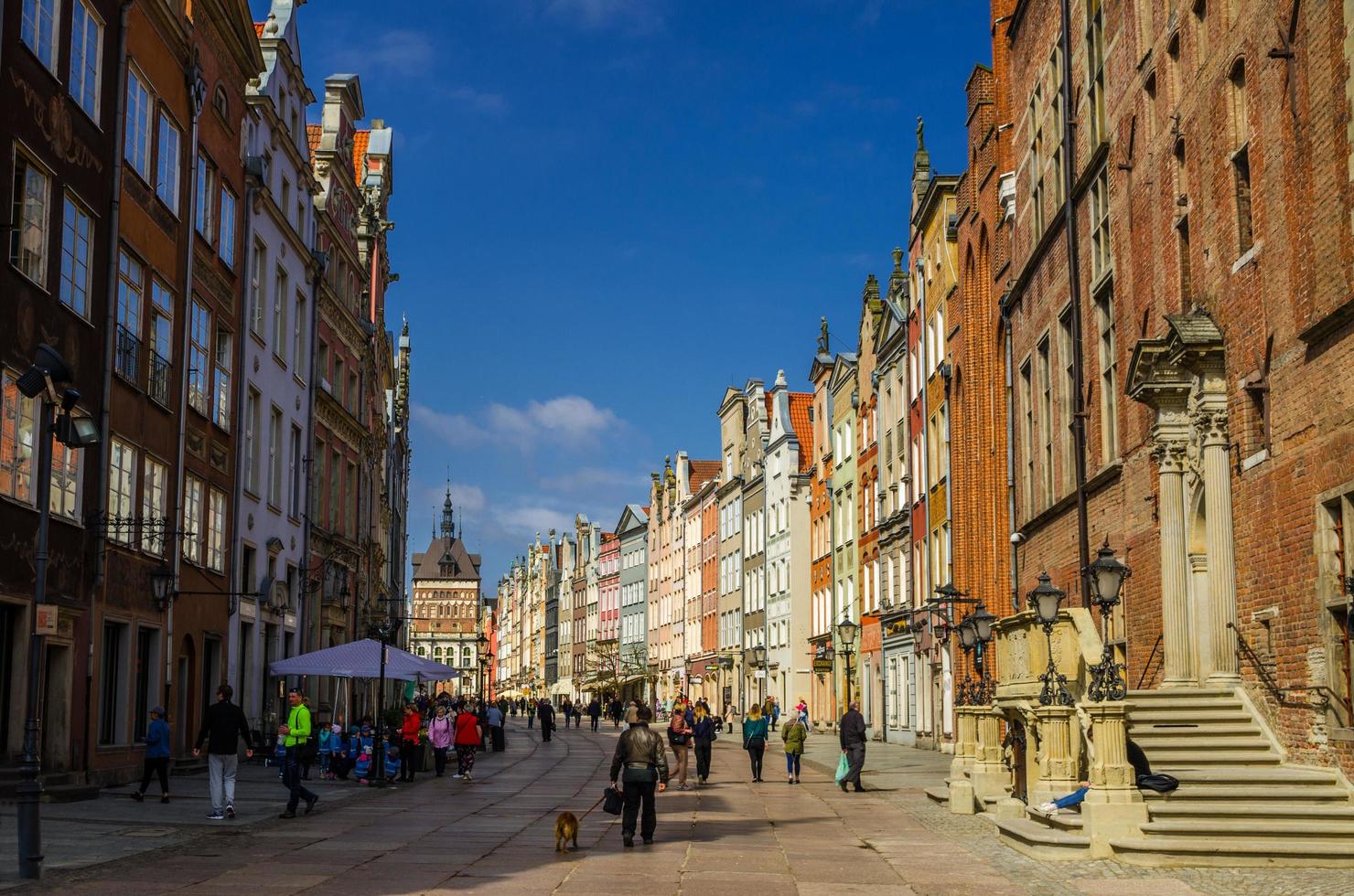 gdansk, polônia, 17 de abril de 2018 golden gate zlota brama, torre de prisão e fachada de belas casas coloridas típicas edifícios e turistas de pessoas andando na rua dluga no antigo centro histórico da cidade foto