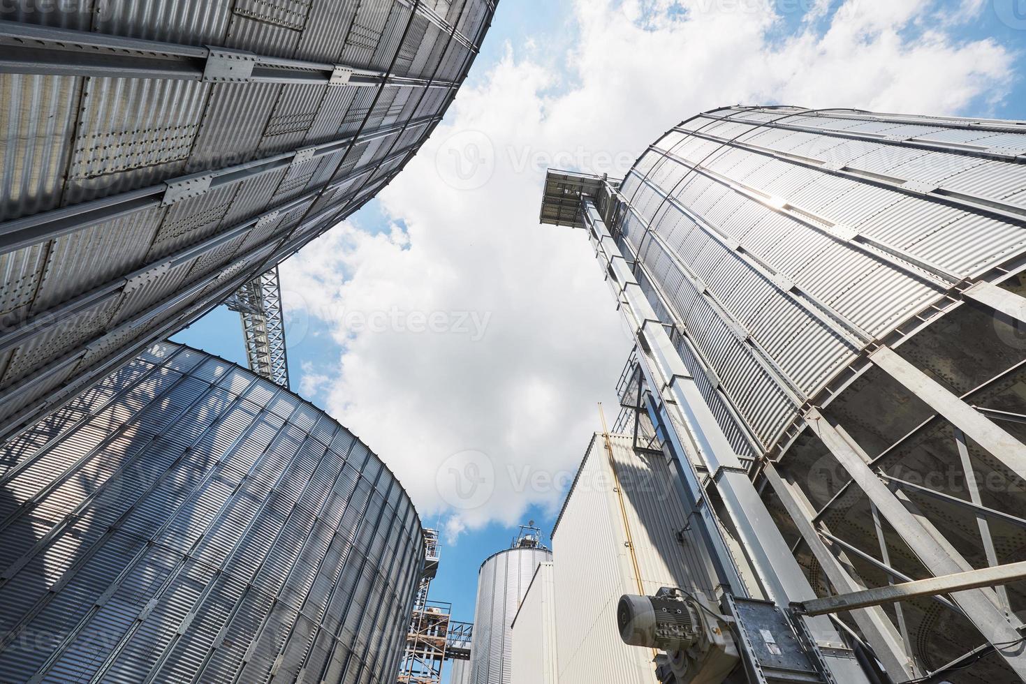 silos agrícolas. exterior do edifício. armazenamento e secagem de grãos, trigo, milho, soja, girassol contra o céu azul com nuvens brancas foto